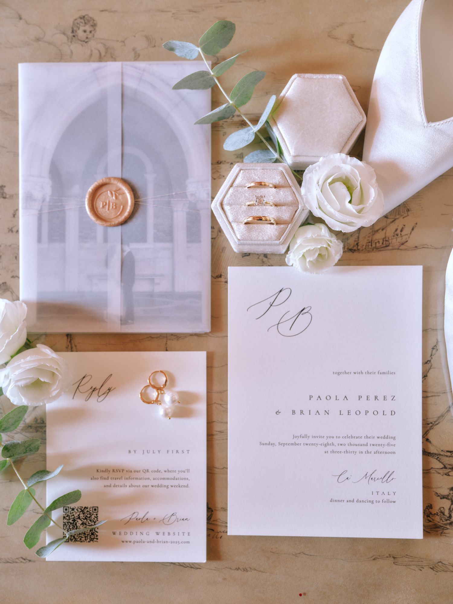 Elegant wedding invitation suite with white cards, copper wax seals, and eucalyptus leaves on a wooden surface.