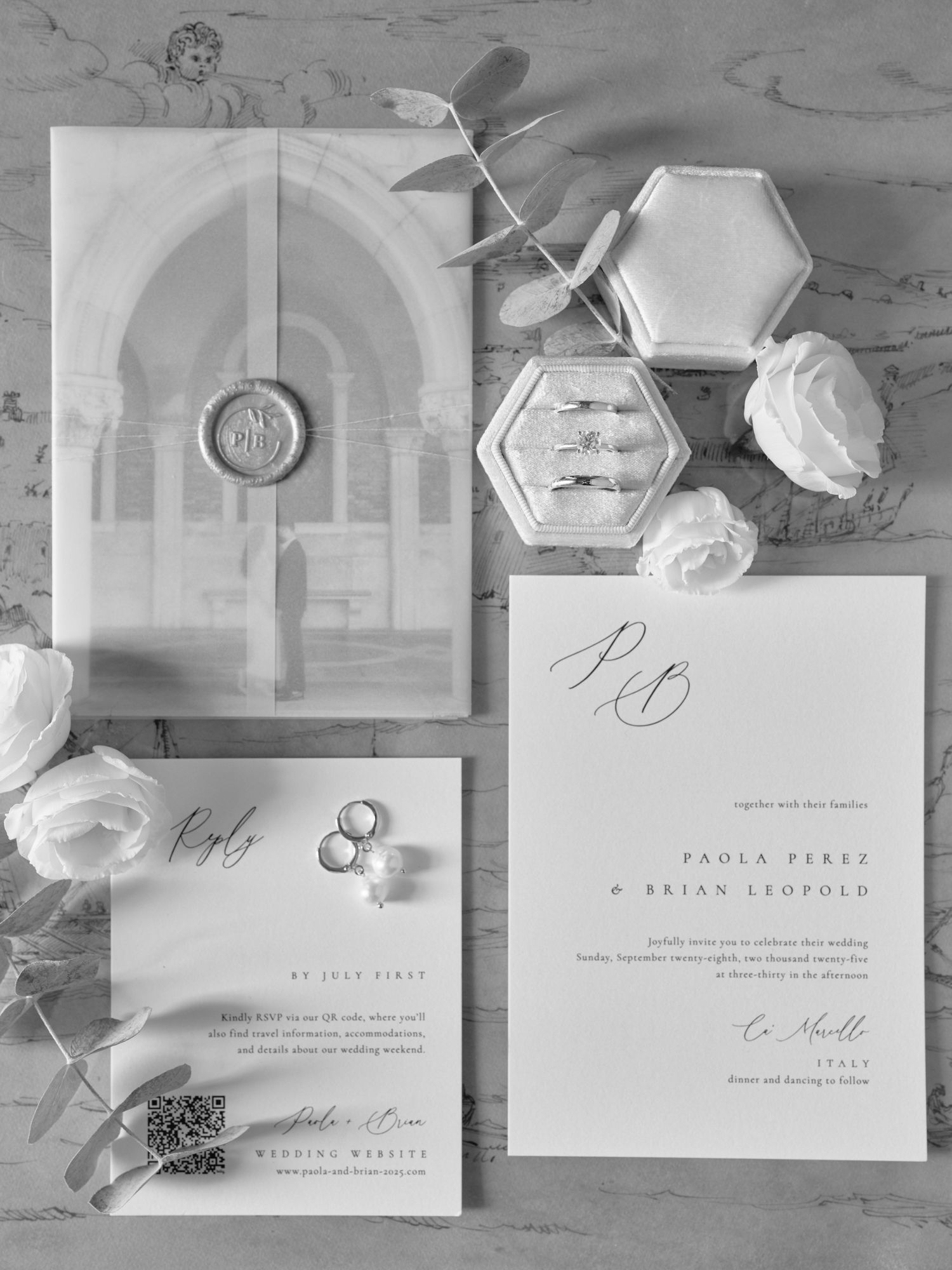 Elegant wedding invitation suite in black and white with architectural details and floral elements laid out on light surface.