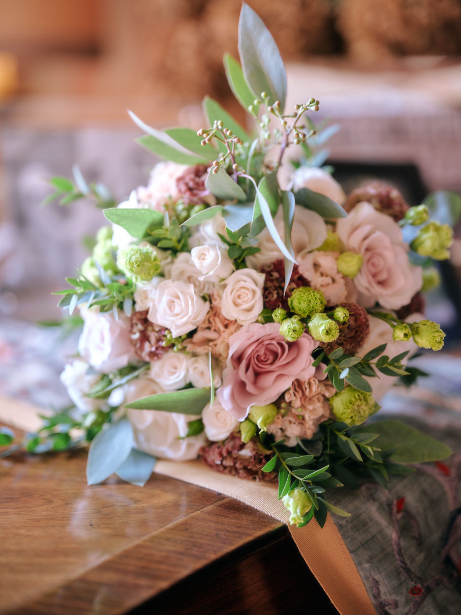 A series of elegant floral arrangements featuring dusty pink roses and mixed greenery on a wooden surface.