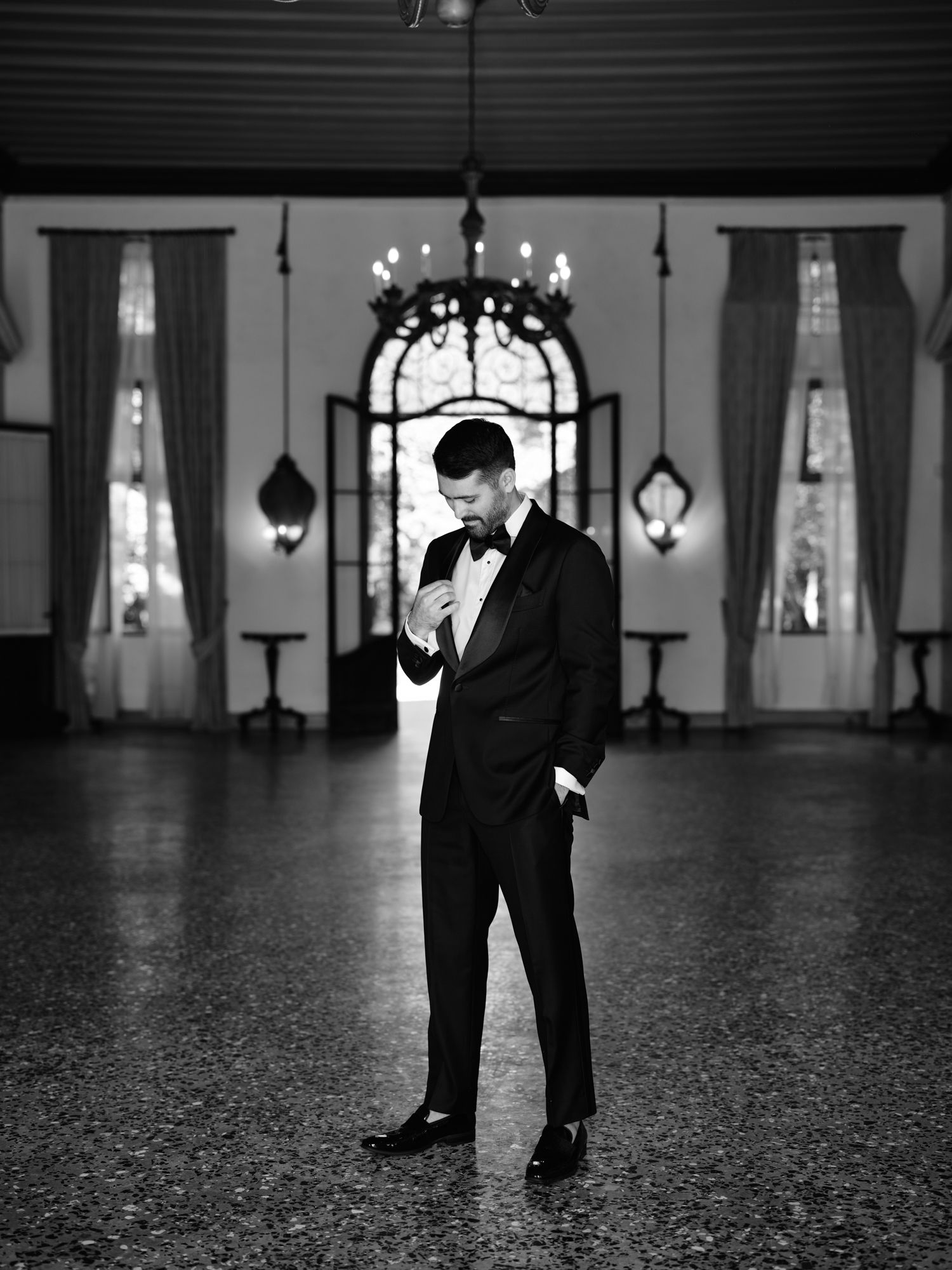 A black and white photo series showing a figure in formal attire standing and moving in an elegant ballroom setting.