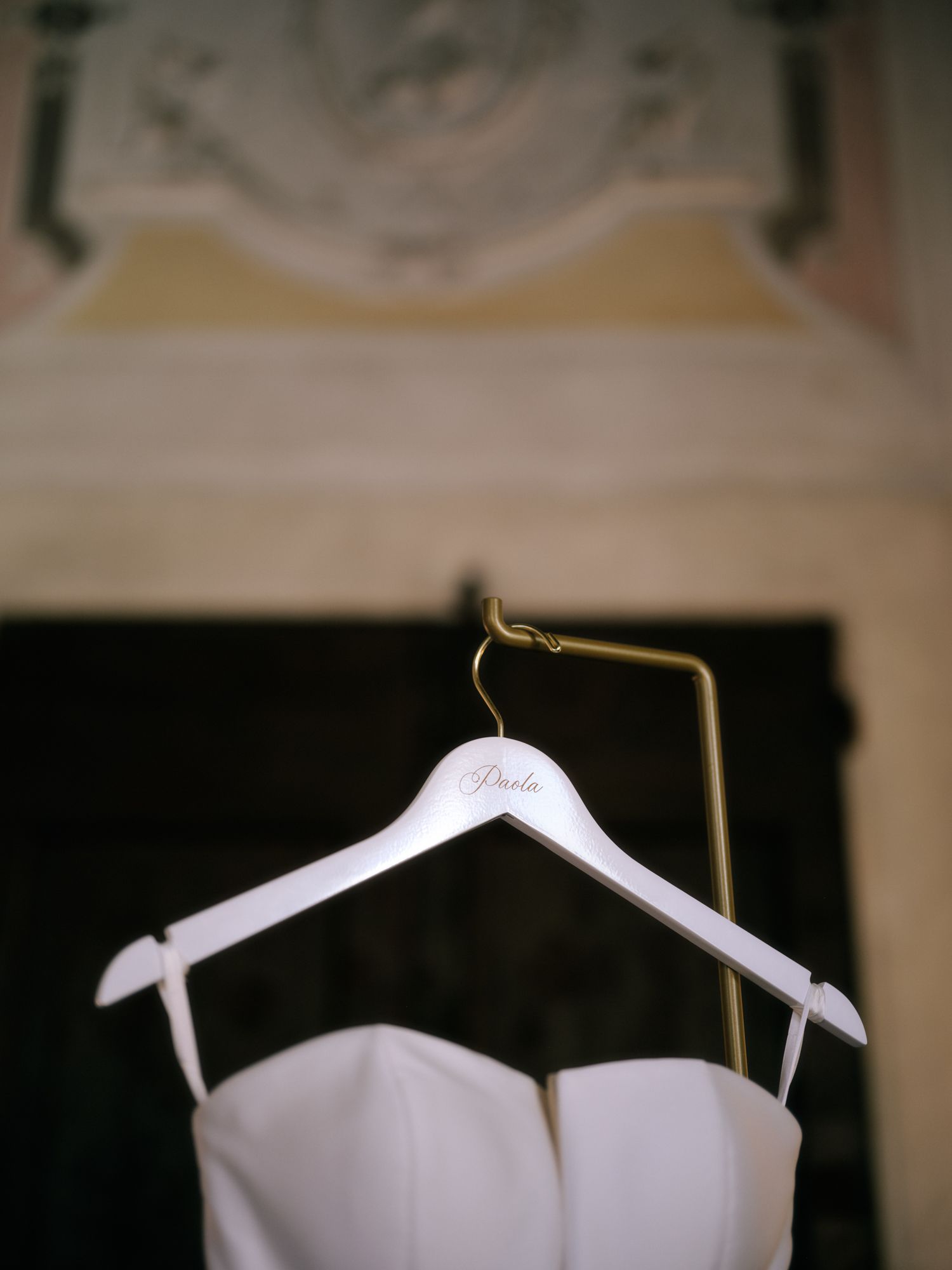 A row of elegant white wedding dresses on hangers displayed against a dark background.