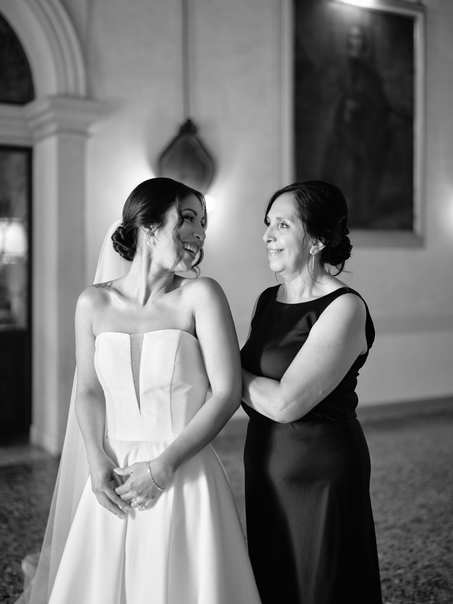 Black and white wedding photos show emotional embraces between people in formal attire during a celebration.