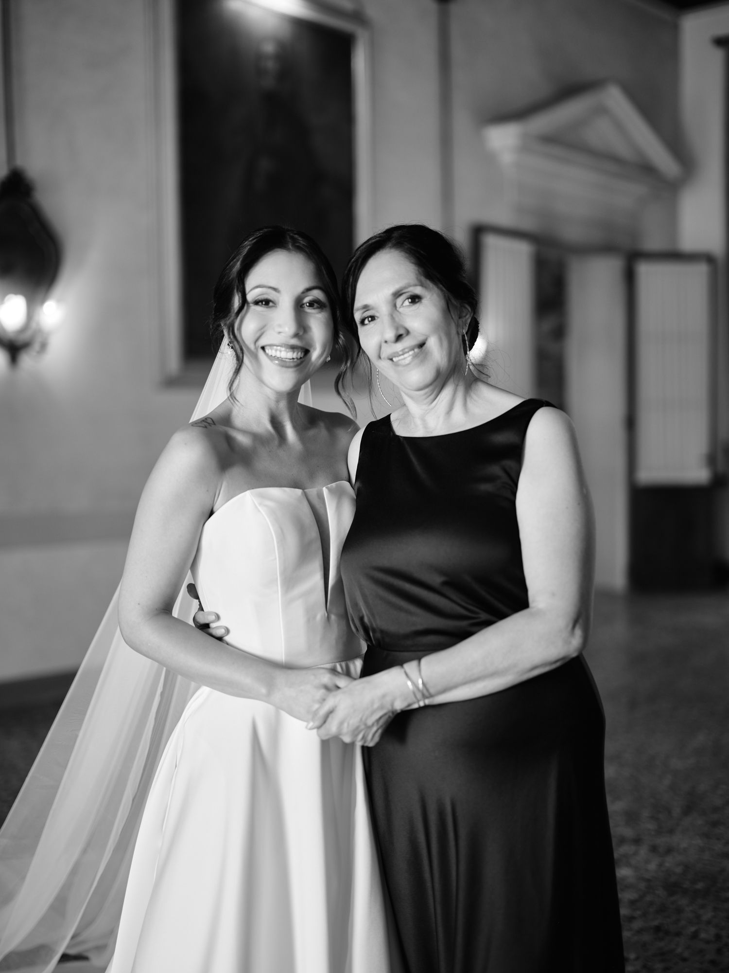 A series of black and white photos showing two people in formal attire hugging and smiling together at an indoor venue.