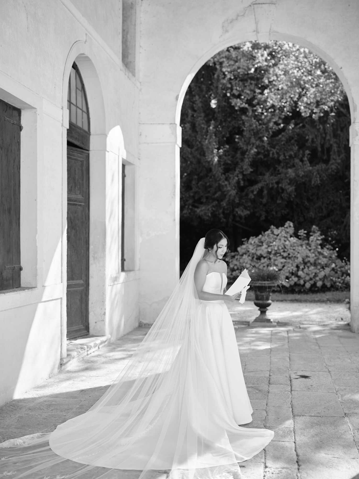 A series of black and white photographs showing ethereal white figures moving through arched stone corridors.