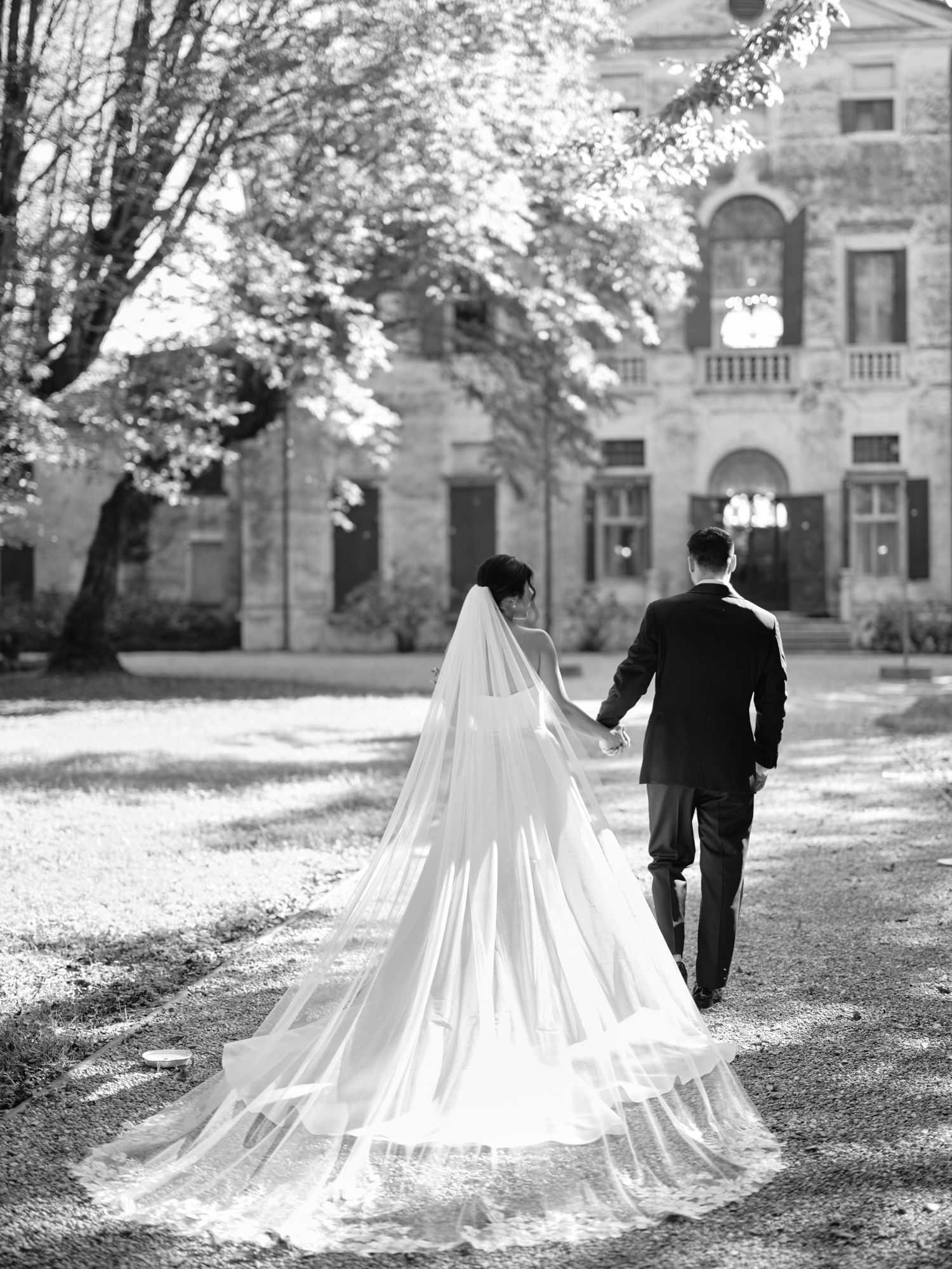 A romantic black and white wedding photo sequence shows a couple walking together on autumn grounds with a flowing cathedral train.