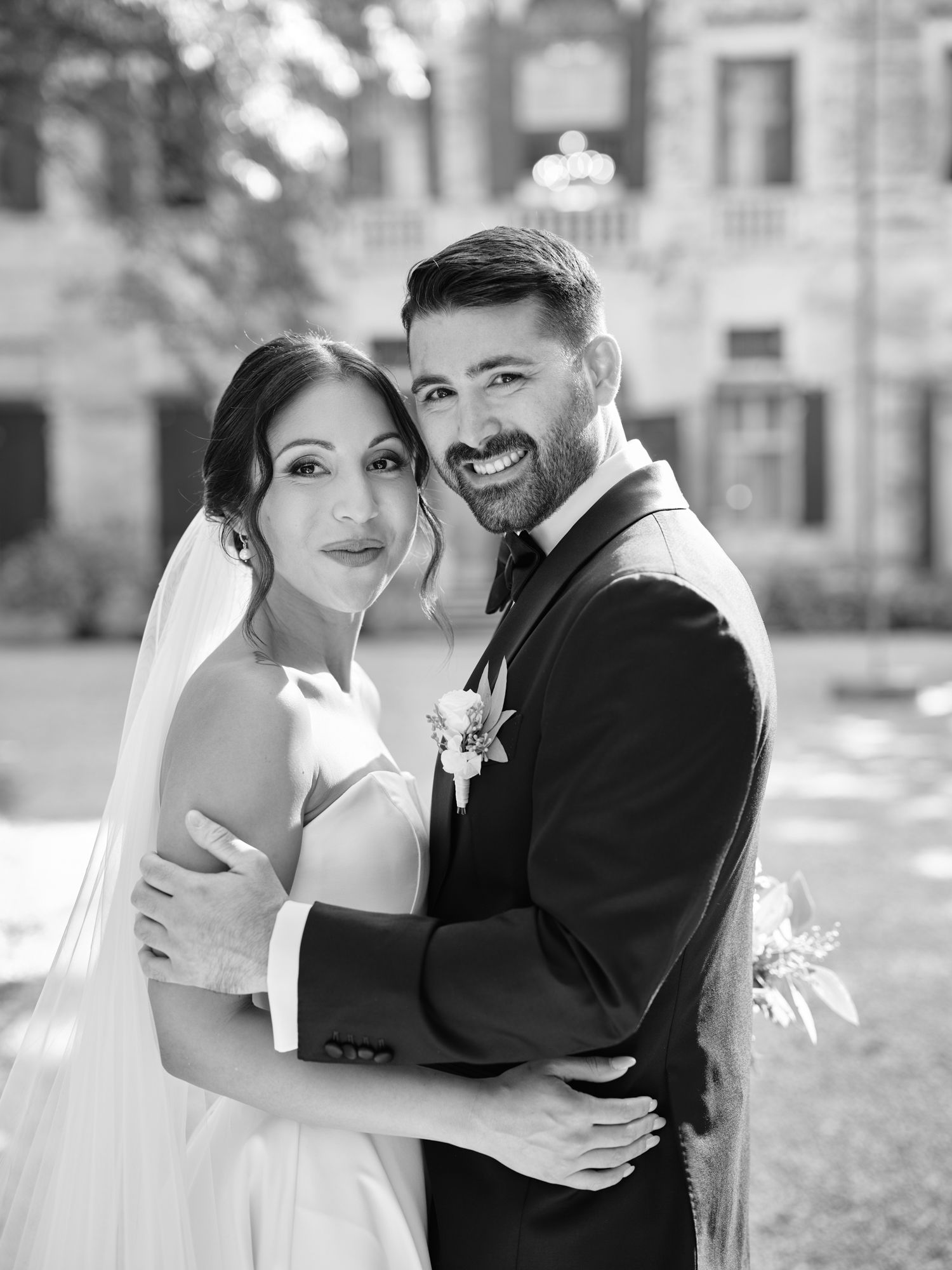A bride and groom share intimate black and white wedding portraits outdoors showing joyful embraces and candid moments.