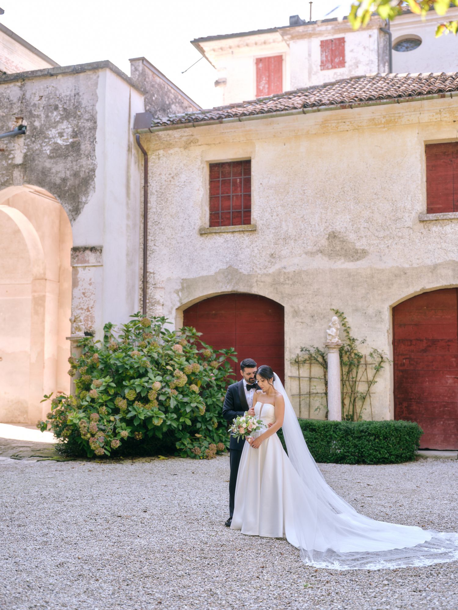 A romantic wedding couple poses in a series of elegant shots against rustic stone walls and architecture.