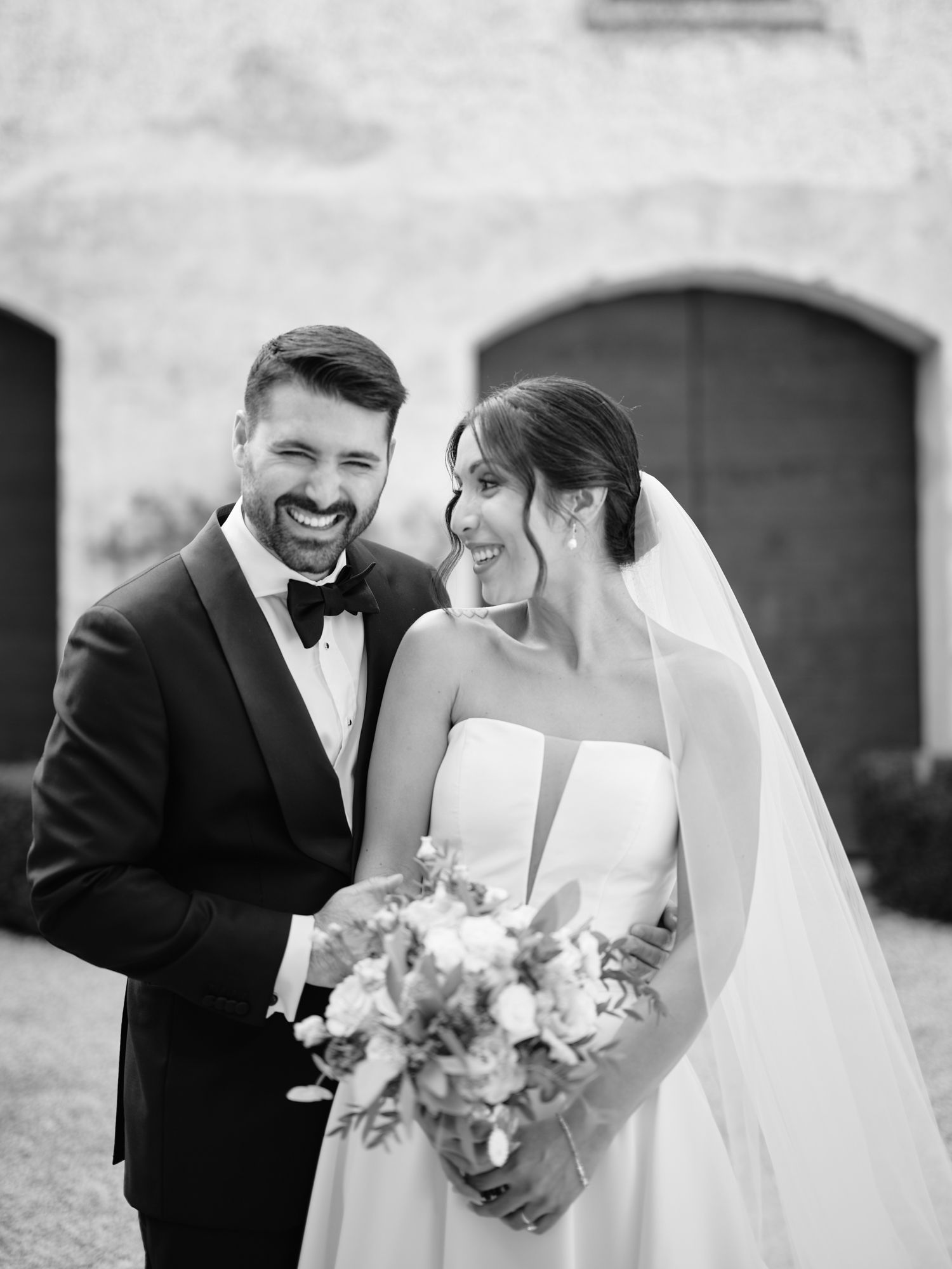 A bride and groom share joyful candid moments in black and white wedding photos.