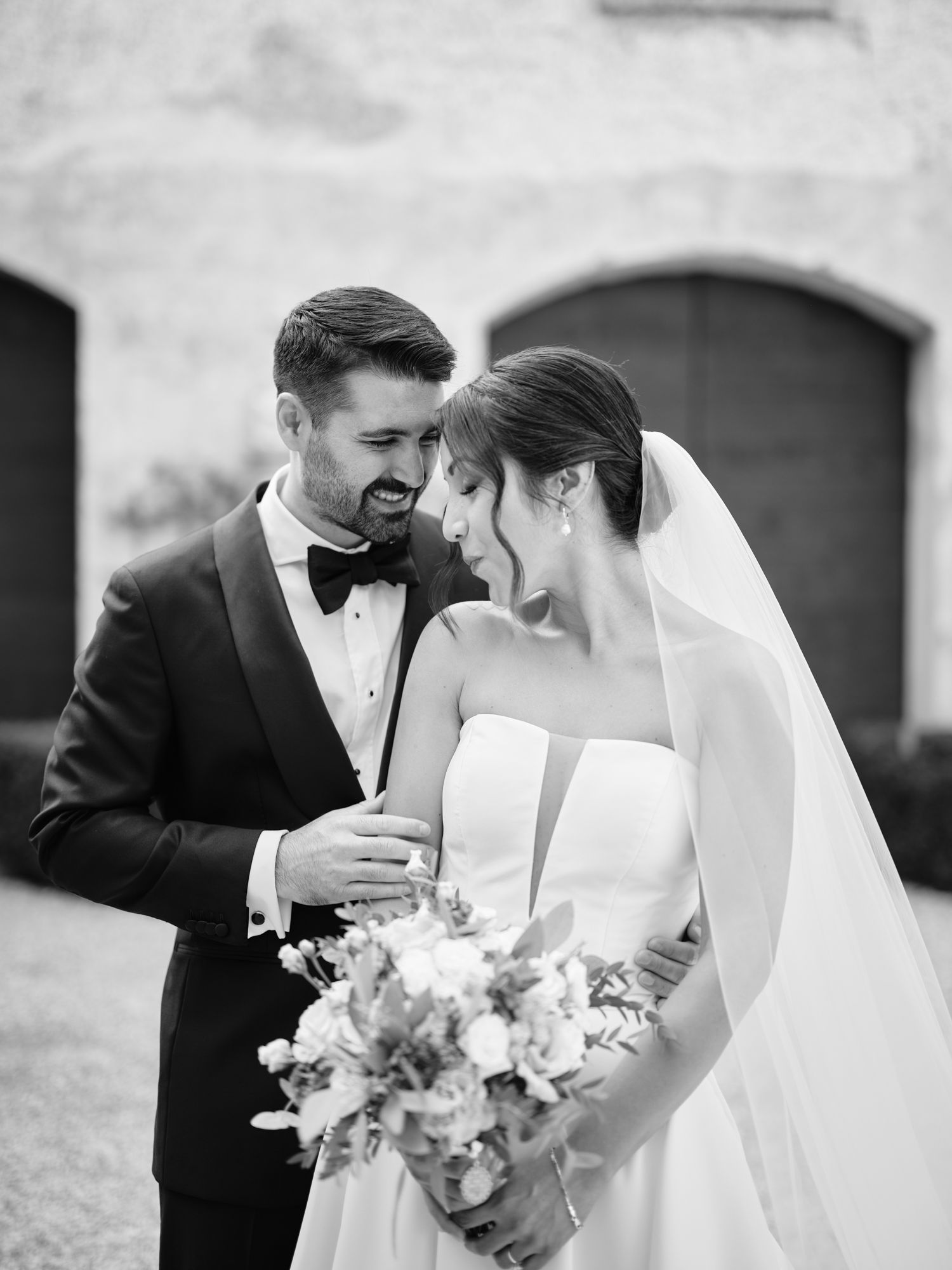 A romantic black and white wedding photo series showing tender moments between a bride and groom with flowers.