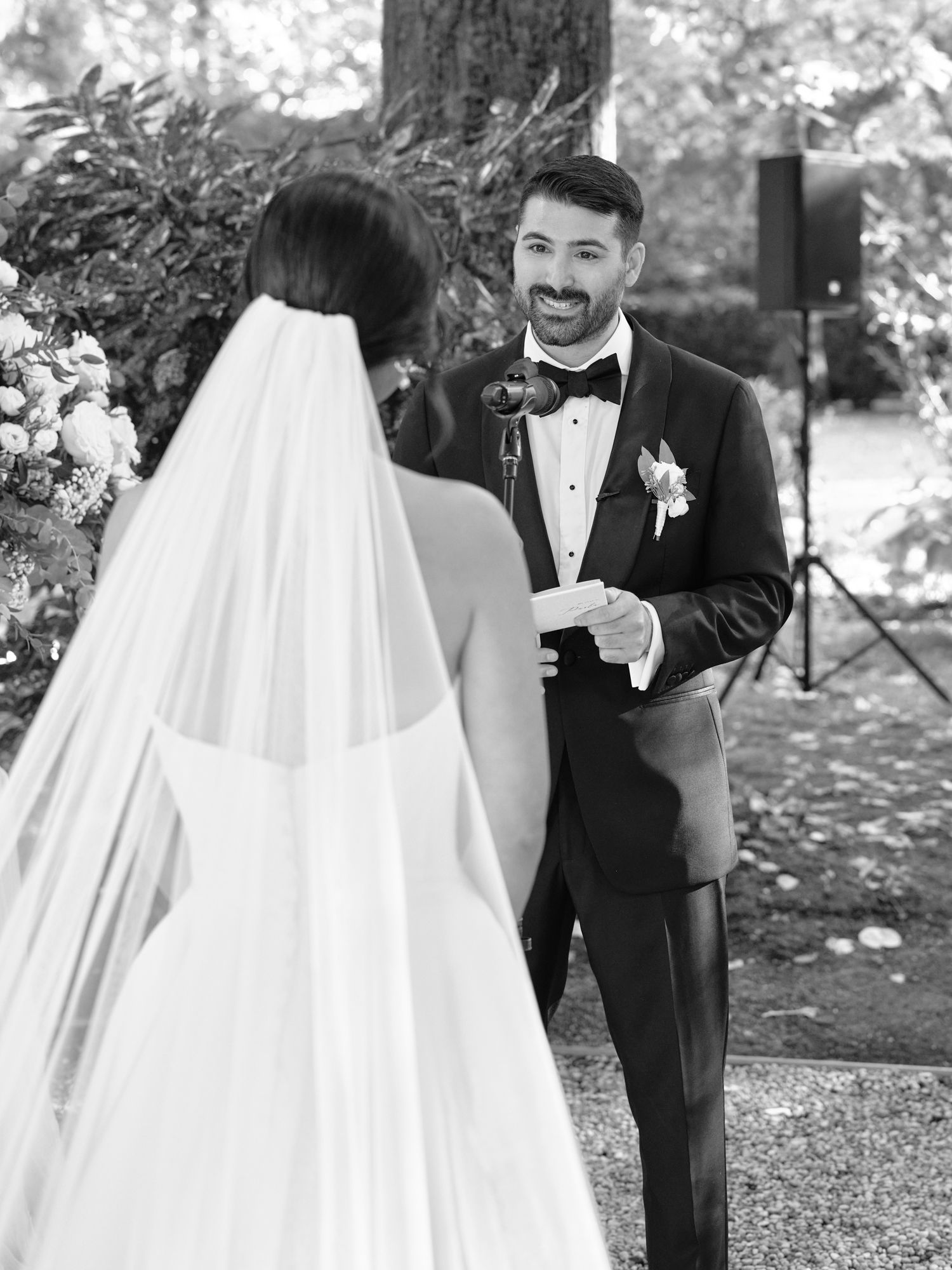 A black and white wedding photo showing a couple during their first look moment in an outdoor garden setting.