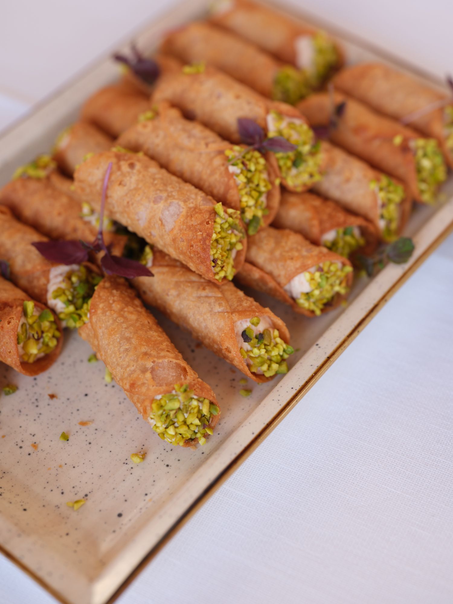 Homemade chocolate cannoli filled with bright green pistachio cream arranged in rows on parchment paper.