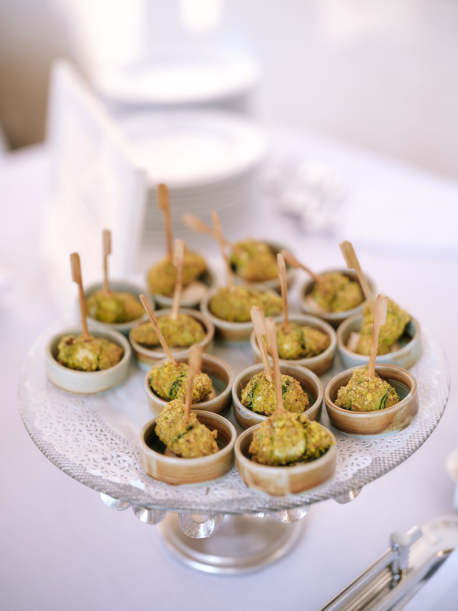 Elegant appetizers of escargot served in individual spoons arranged on a glass serving platter.