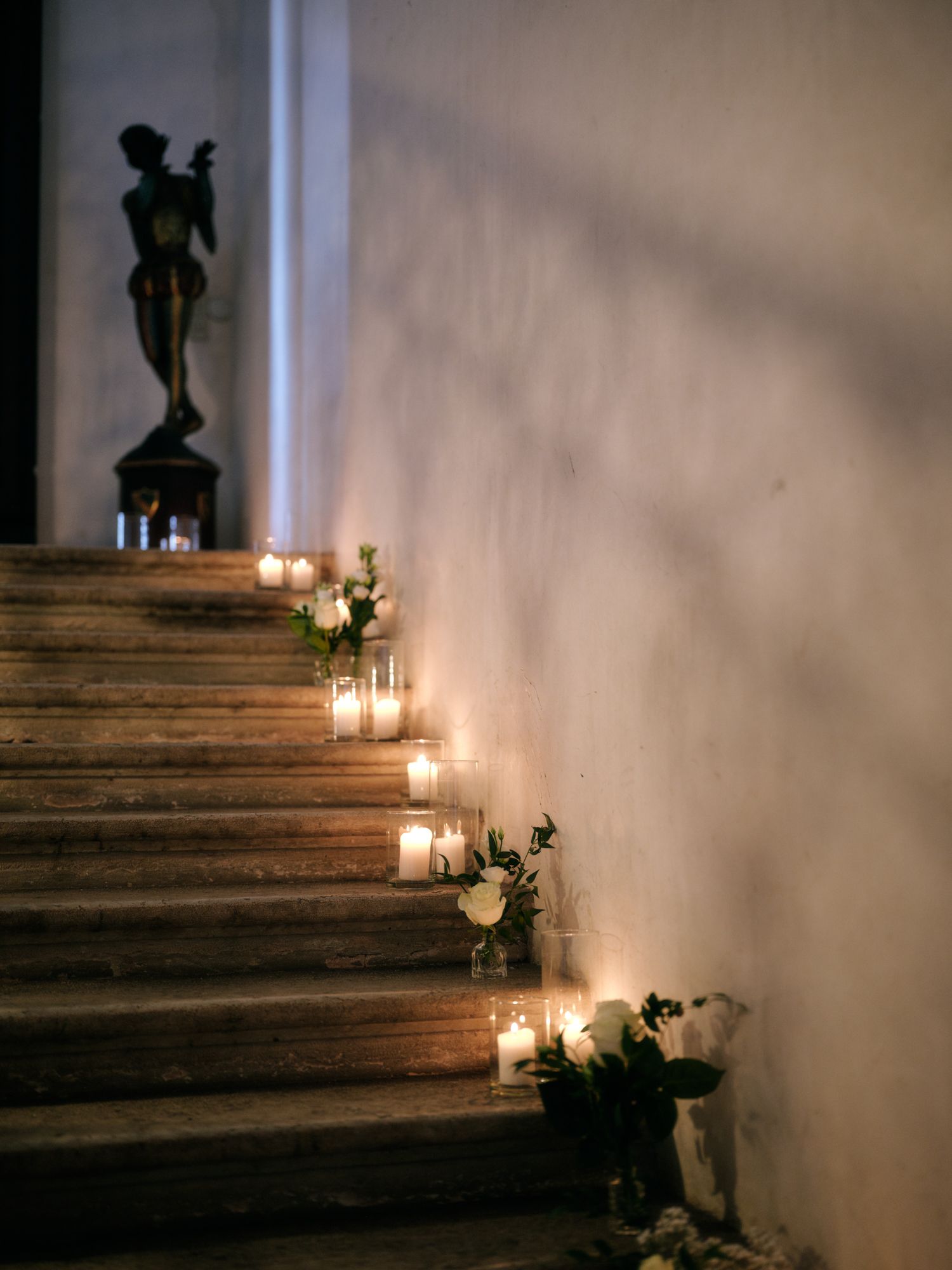 Lit candles and floral decorations line rustic wooden stairs creating a romantic ambiance in dim lighting.