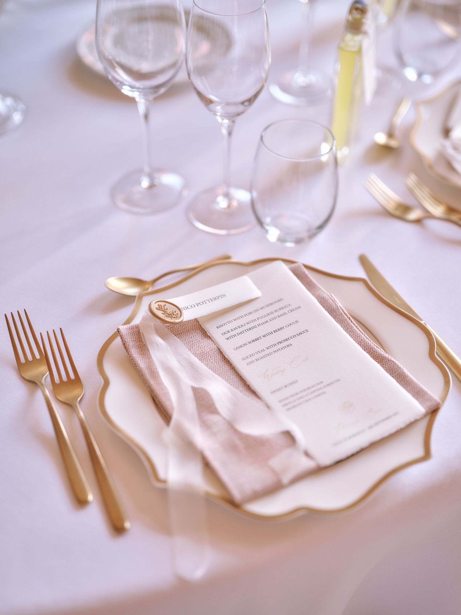 Elegant table settings with white linens, wine glasses, and gold cutlery arranged for a formal dining event.