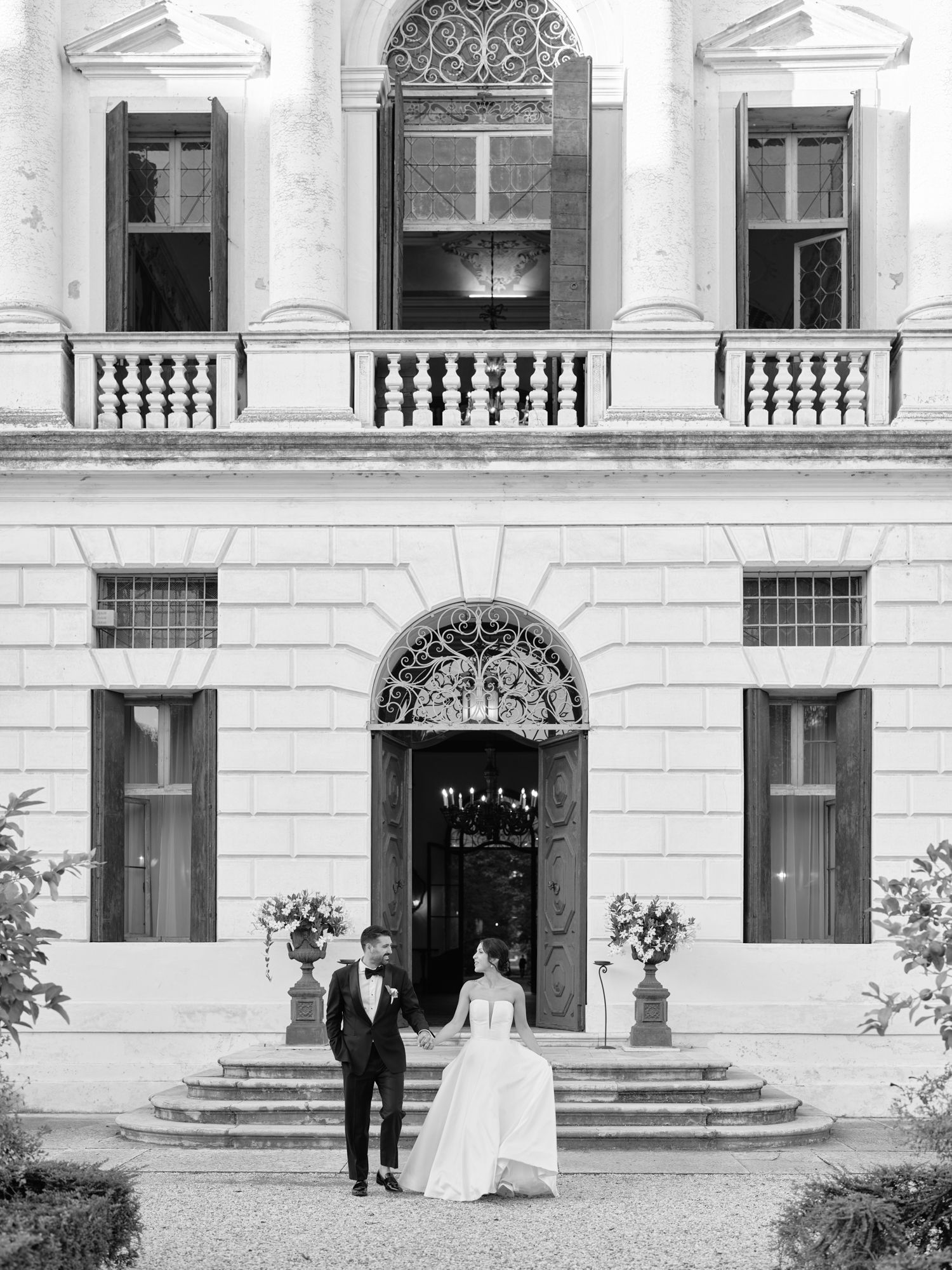 A classic black and white wedding photo series showing a couple walking down the grand steps of an elegant mansion.