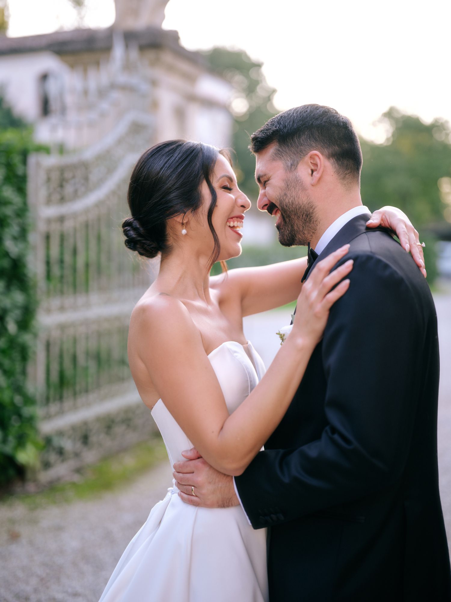 A romantic wedding couple shares an intimate moment together outdoors near an elegant white building.