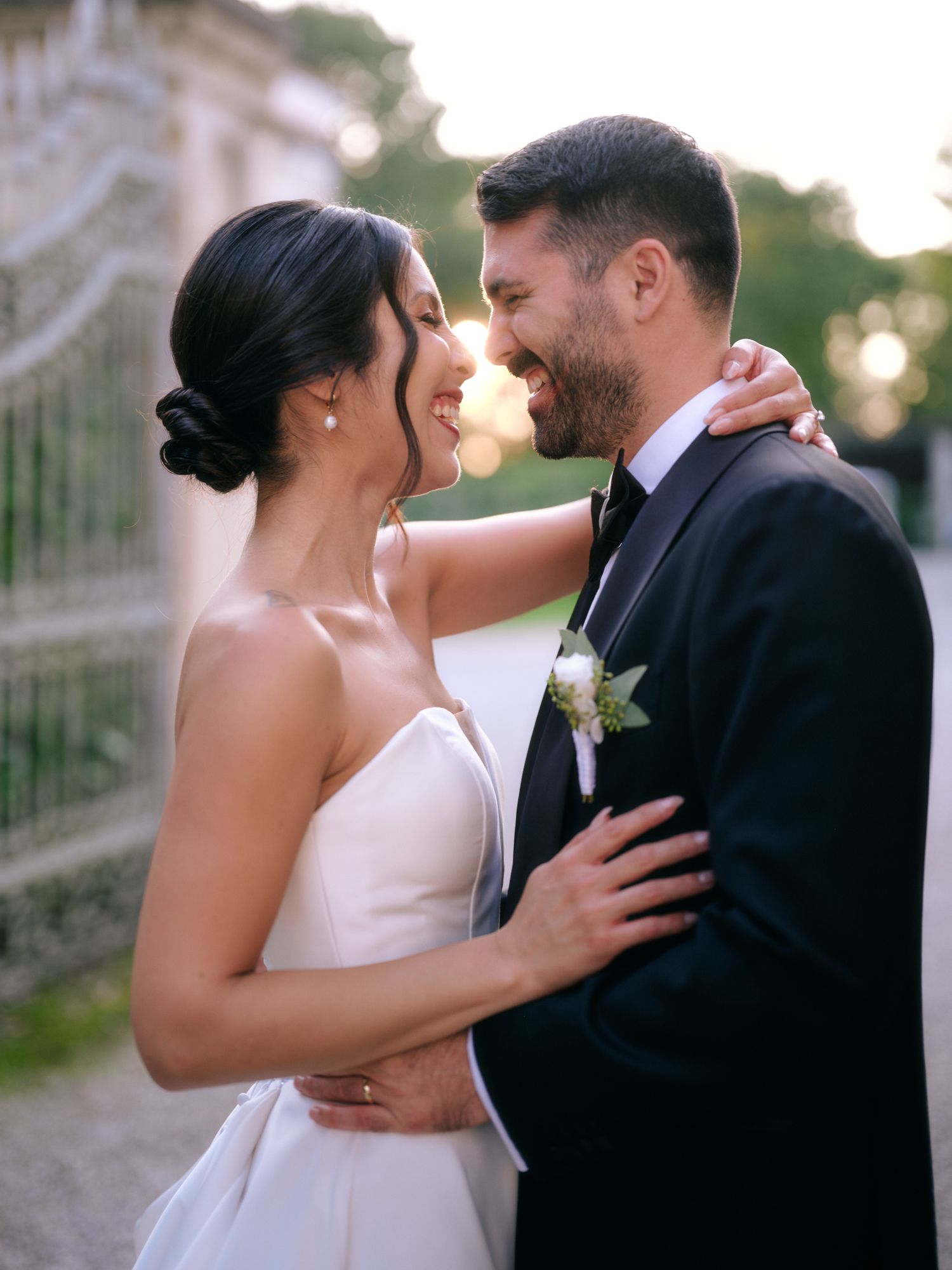 Romantic wedding couple shares intimate moments during outdoor sunset photo session in a garden setting.