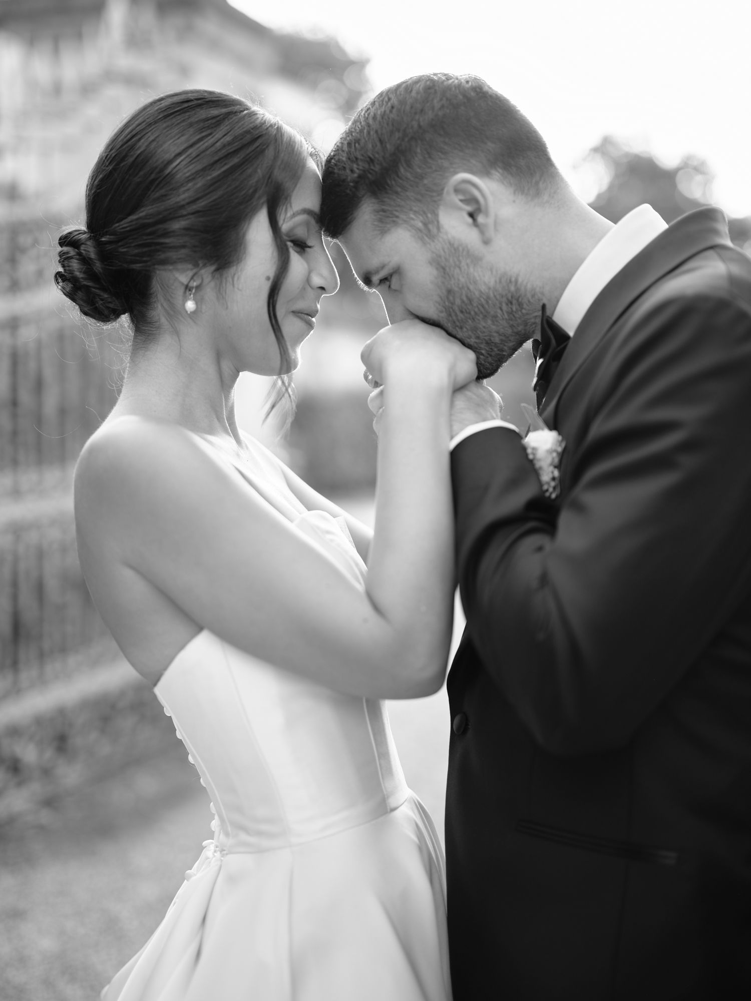 Black and white wedding photos show intimate moments between a couple in formal attire sharing romantic kisses.