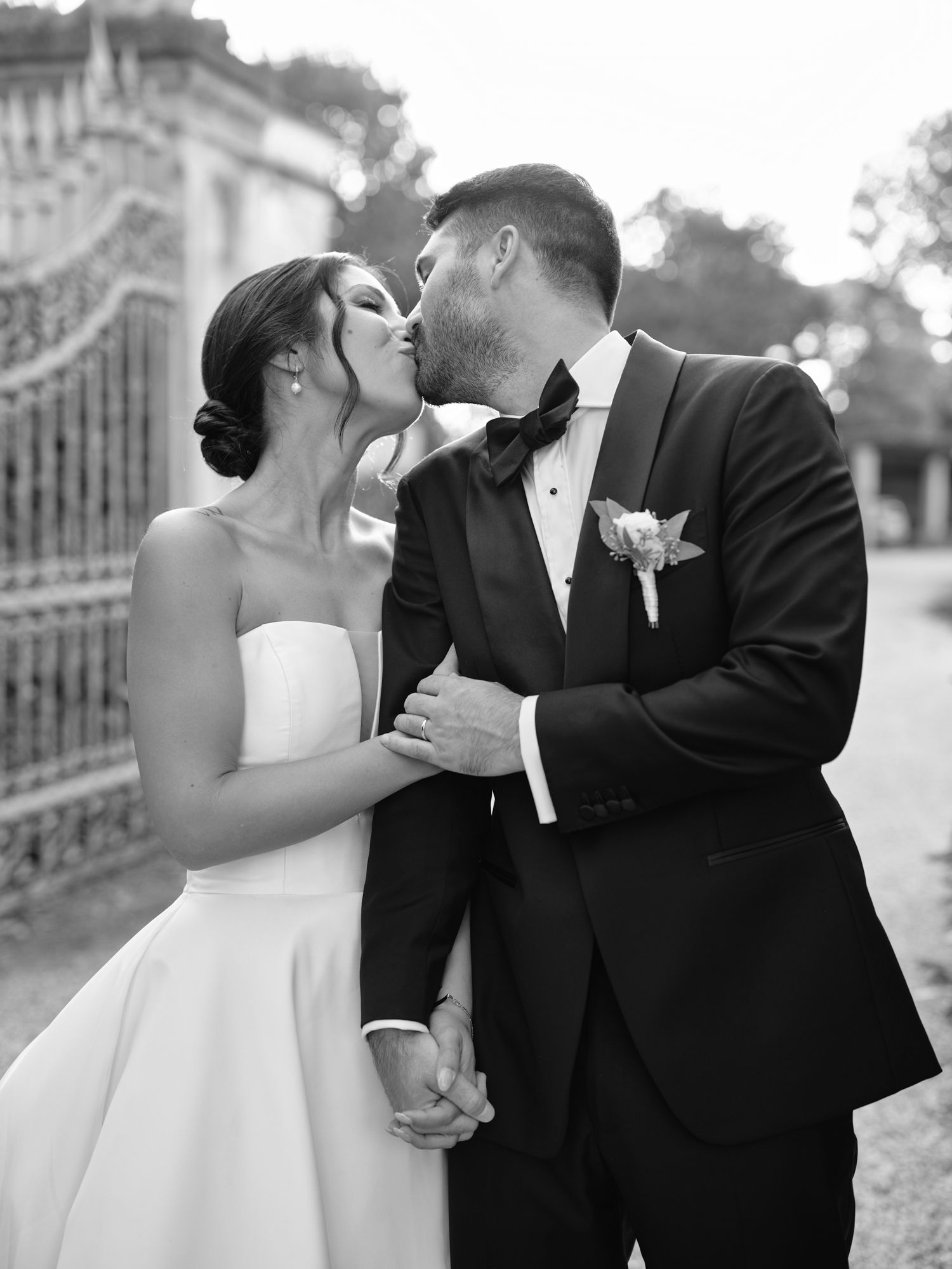 A romantic black and white photo series showing a couple in wedding attire sharing intimate kisses outdoors.