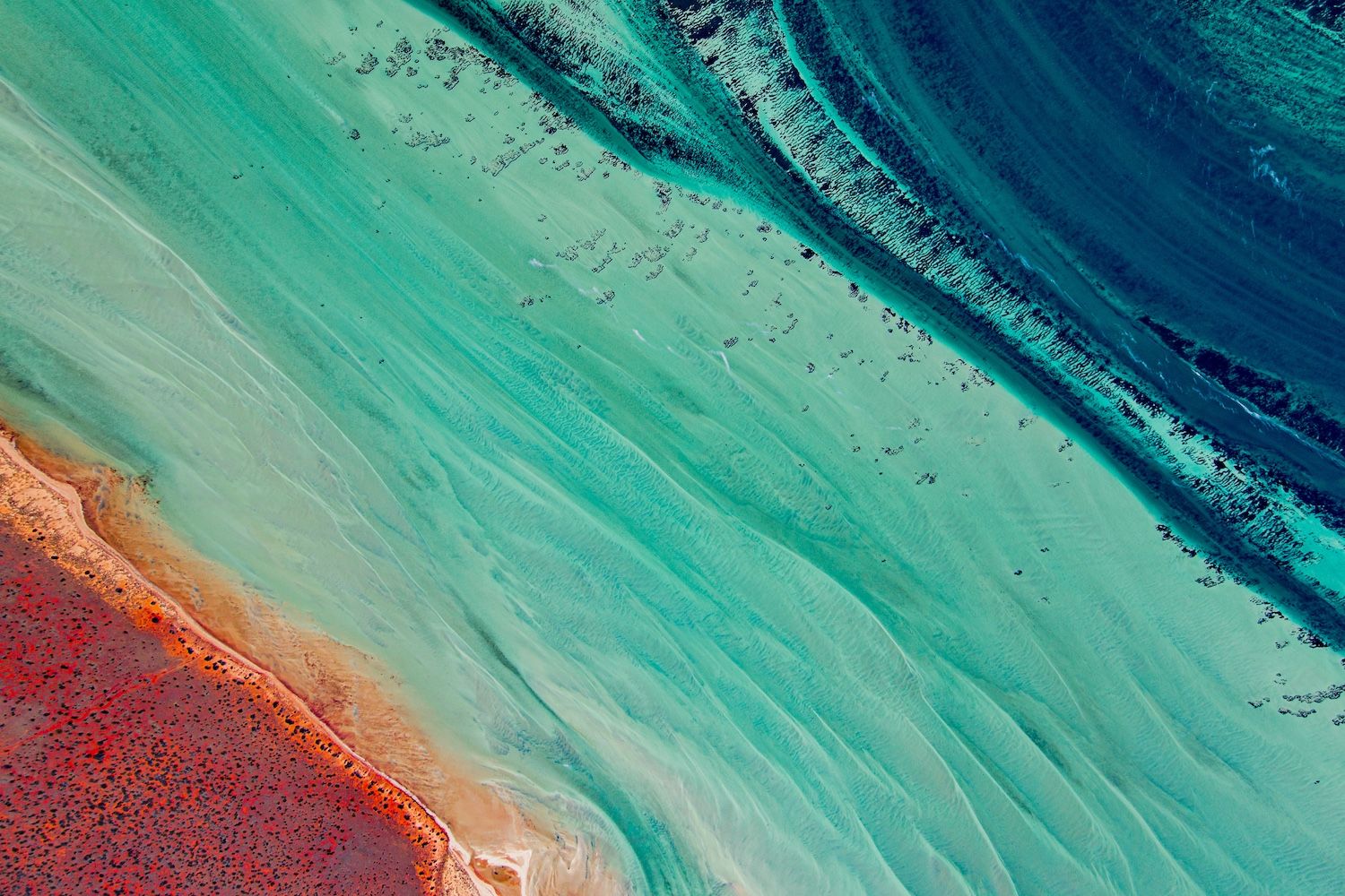 Aerial view of turquoise ocean meeting red earth coastline in Western Australia