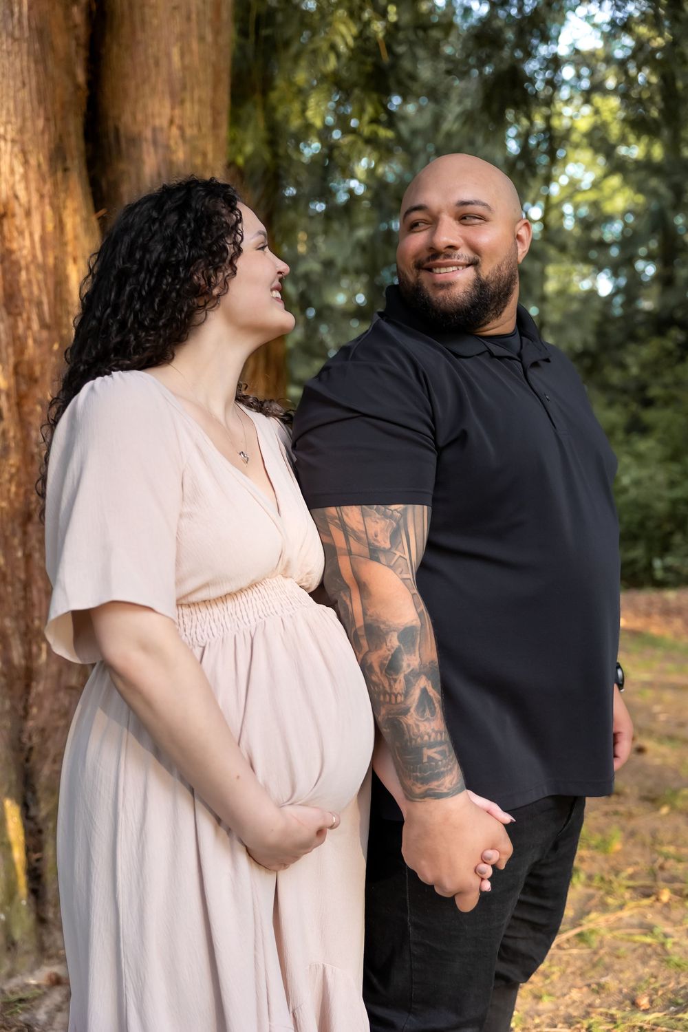 A couple embraces and laughs together during a romantic outdoor photo session among tall trees.