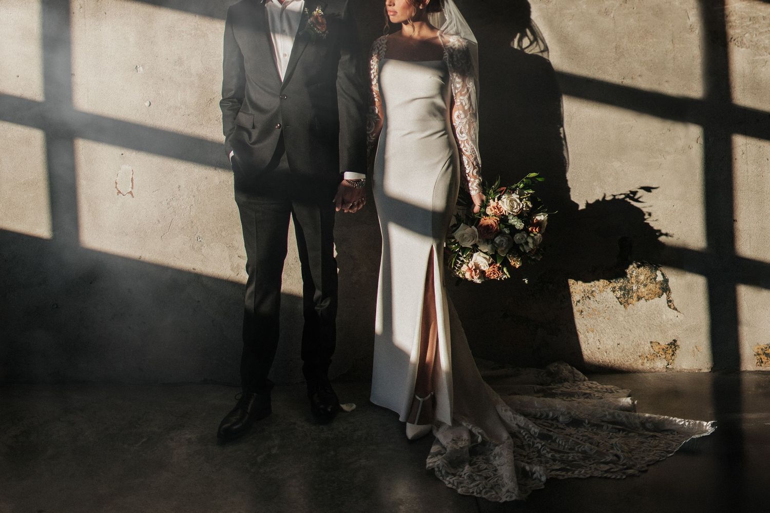 Minimalist wedding portrait with strong shadow play on concrete wall.