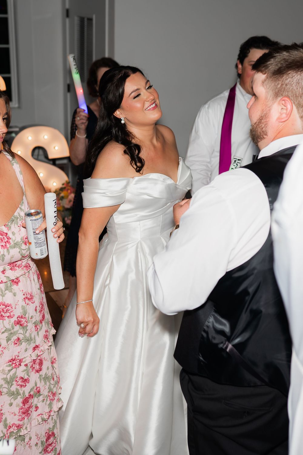 Wedding celebration with guests dancing and holding light-up party favors.