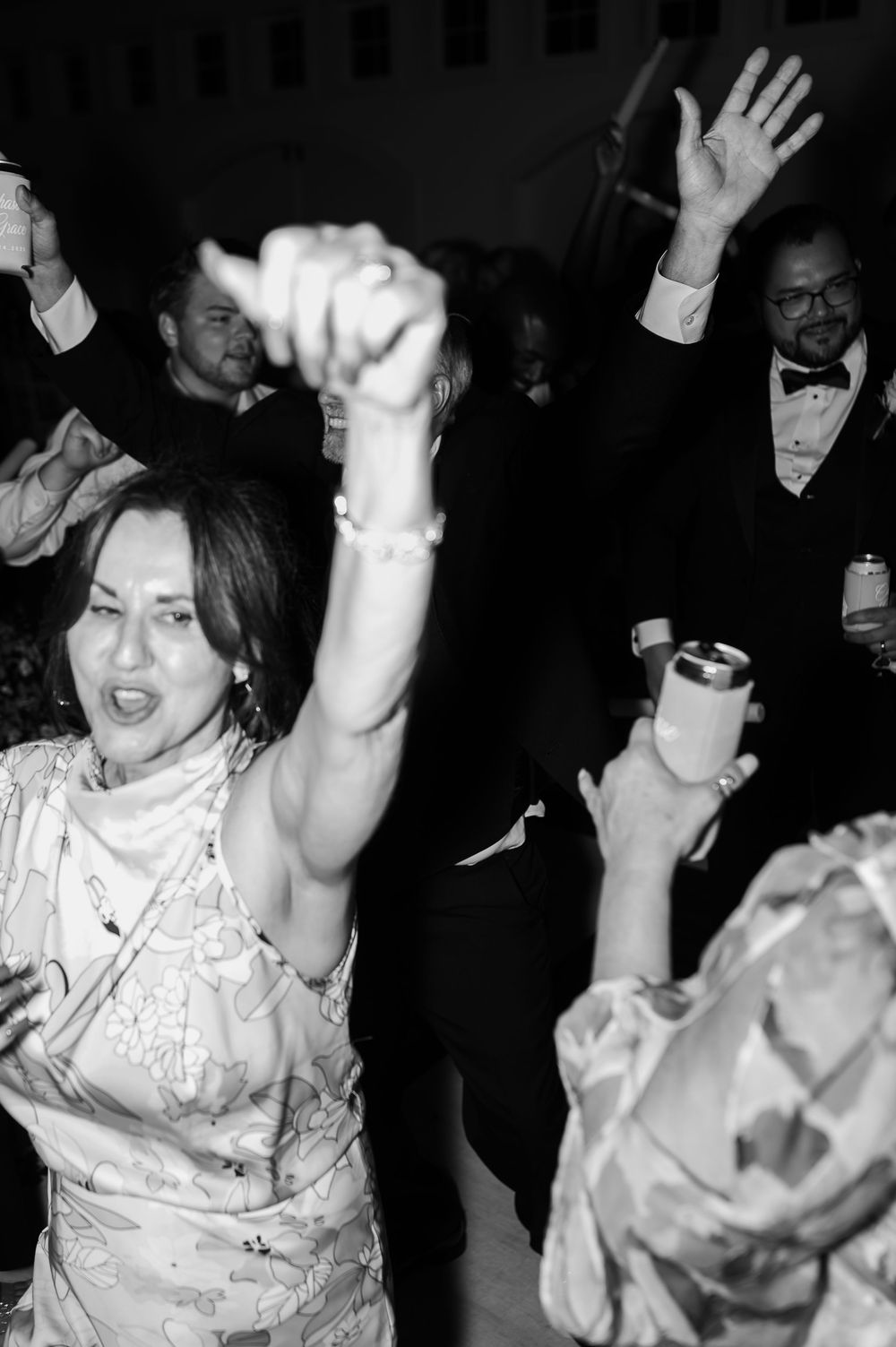 People dancing enthusiastically at a dimly lit wedding reception party.