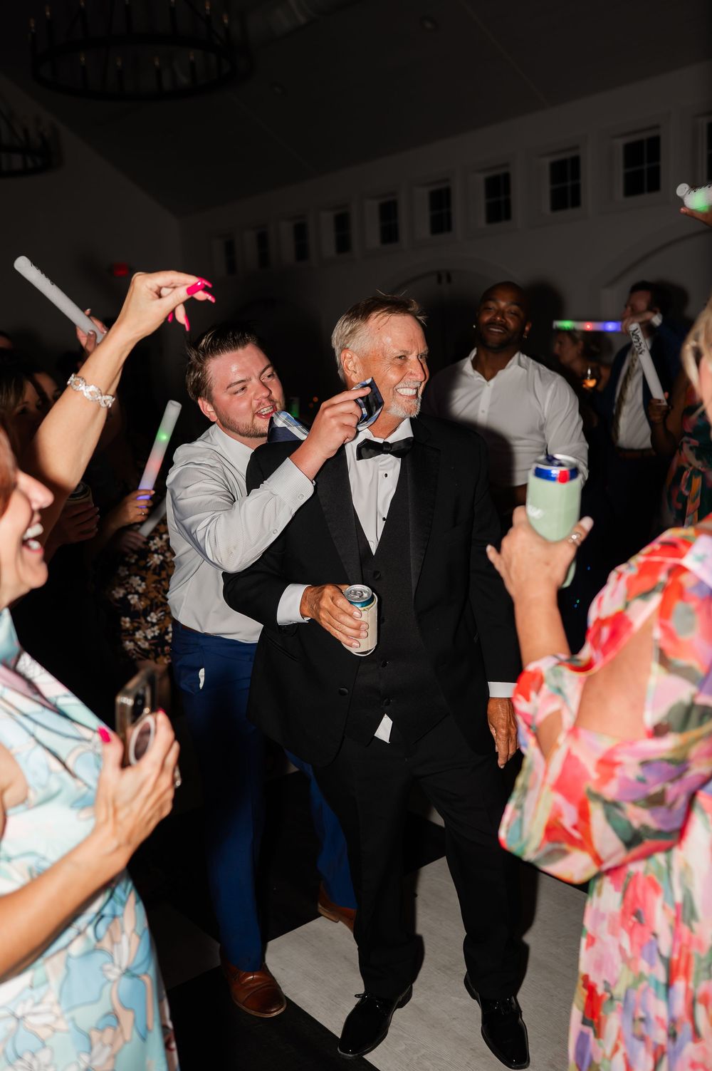 Wedding party guests dancing and having fun with glow sticks on the dance floor.