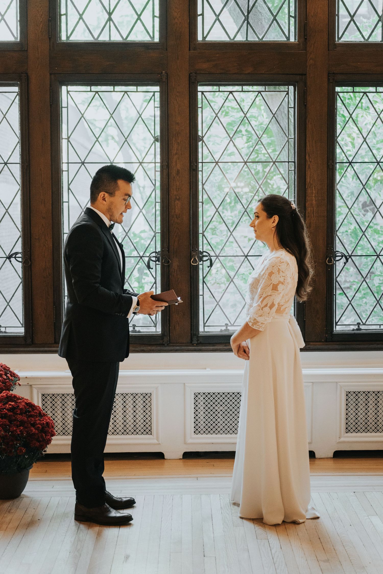 A couple shares a tender moment during their first look in a room with diamond-patterned windows.