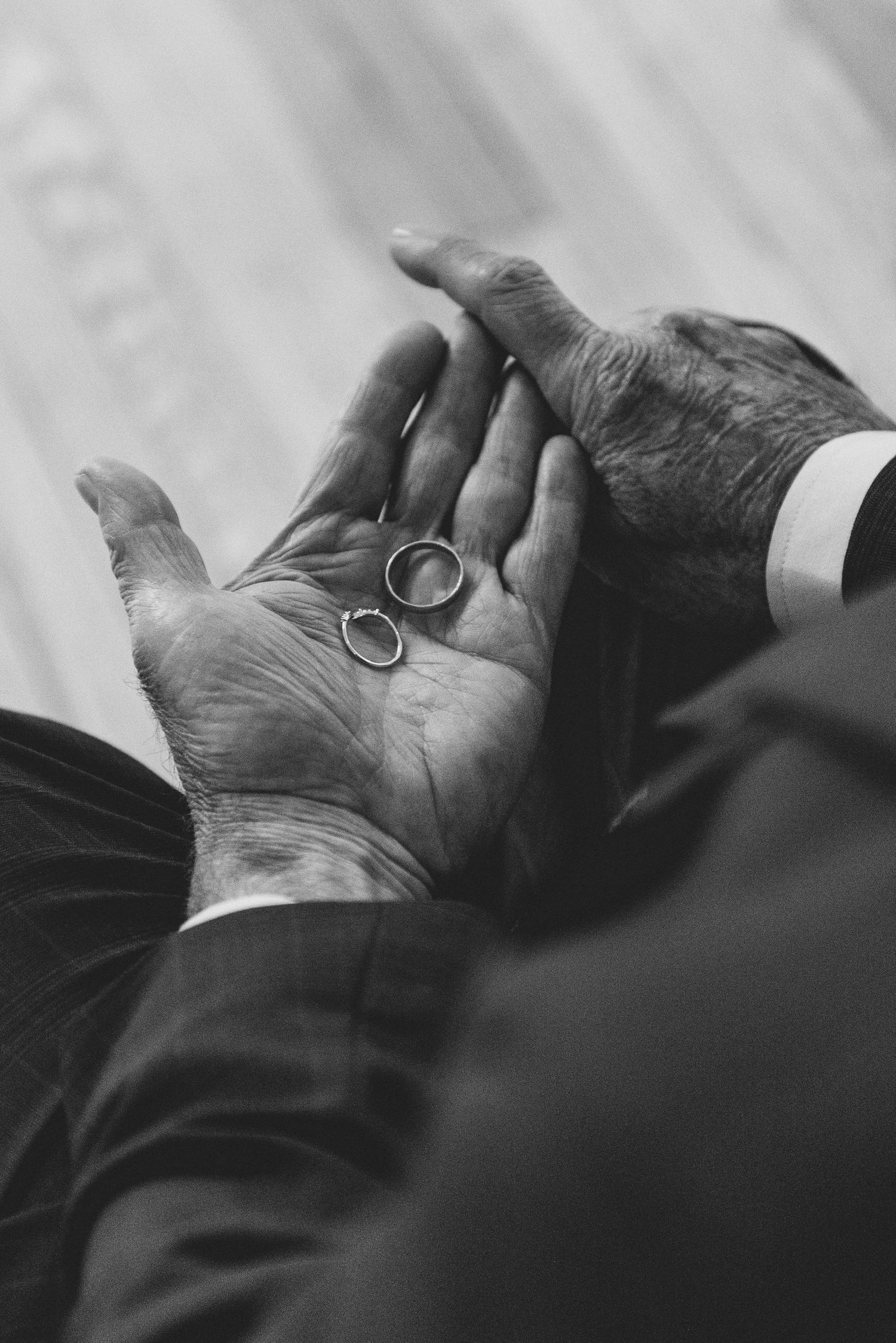 Black and white close-up of hands holding a wedding ring in an intimate moment.