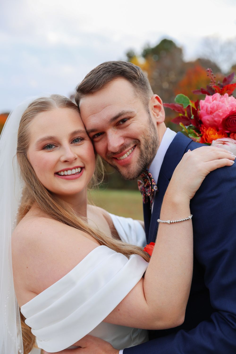 A close-up portrait of newlyweds sharing an intimate moment against a backdrop of fall colors.
