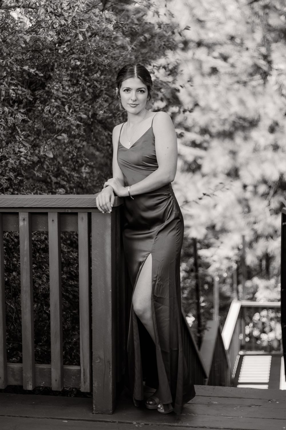 Black and white photo series showing a person in a dark dress posing on a wooden deck with trees in background.
