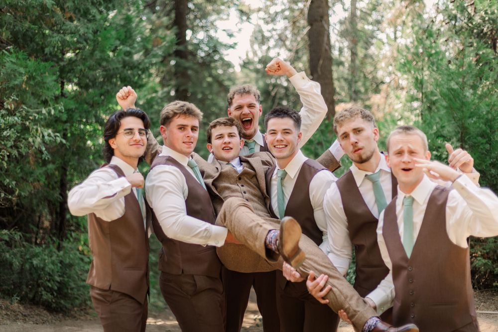 Wedding party in brown vests poses playfully in a wooded outdoor setting for candid photo series.