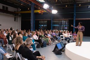 Wide shot of conference audience seated in rows watching presentation.