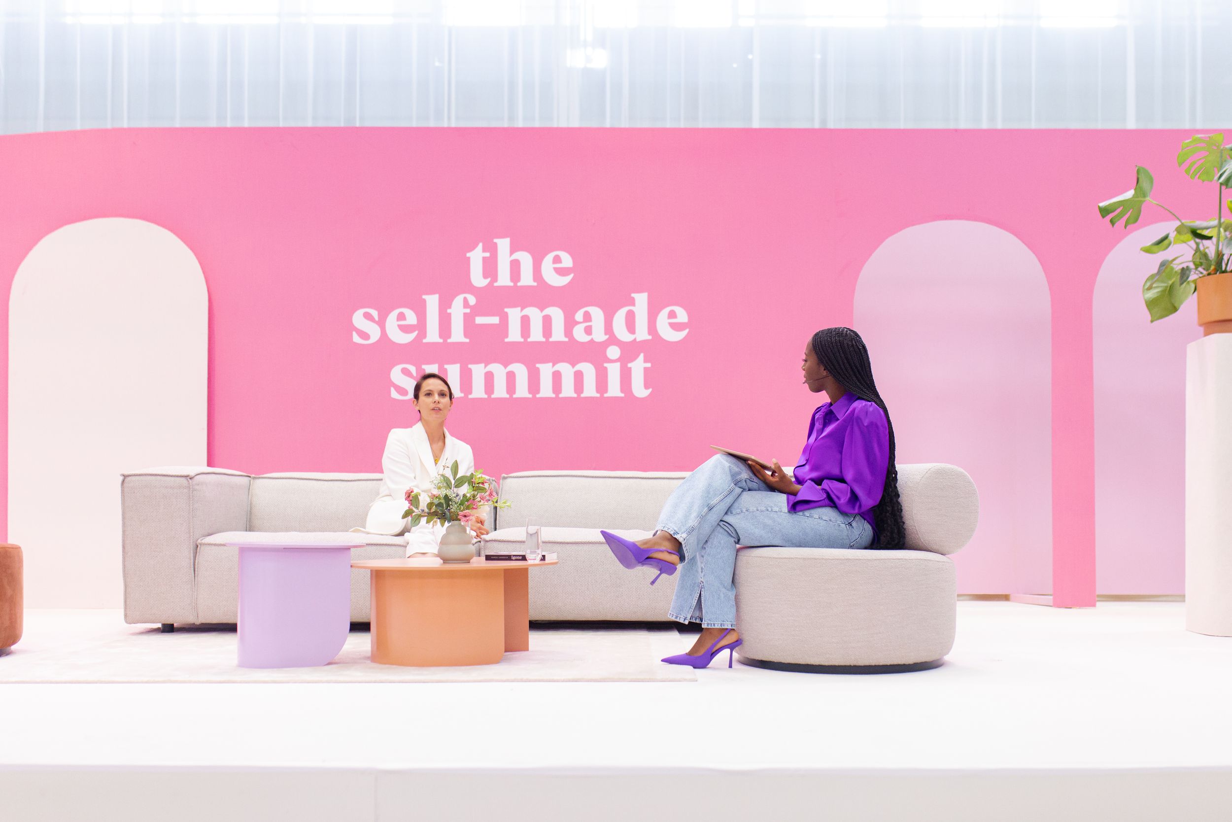 Pink stage setup with white furniture and 'self-made summit' text display.