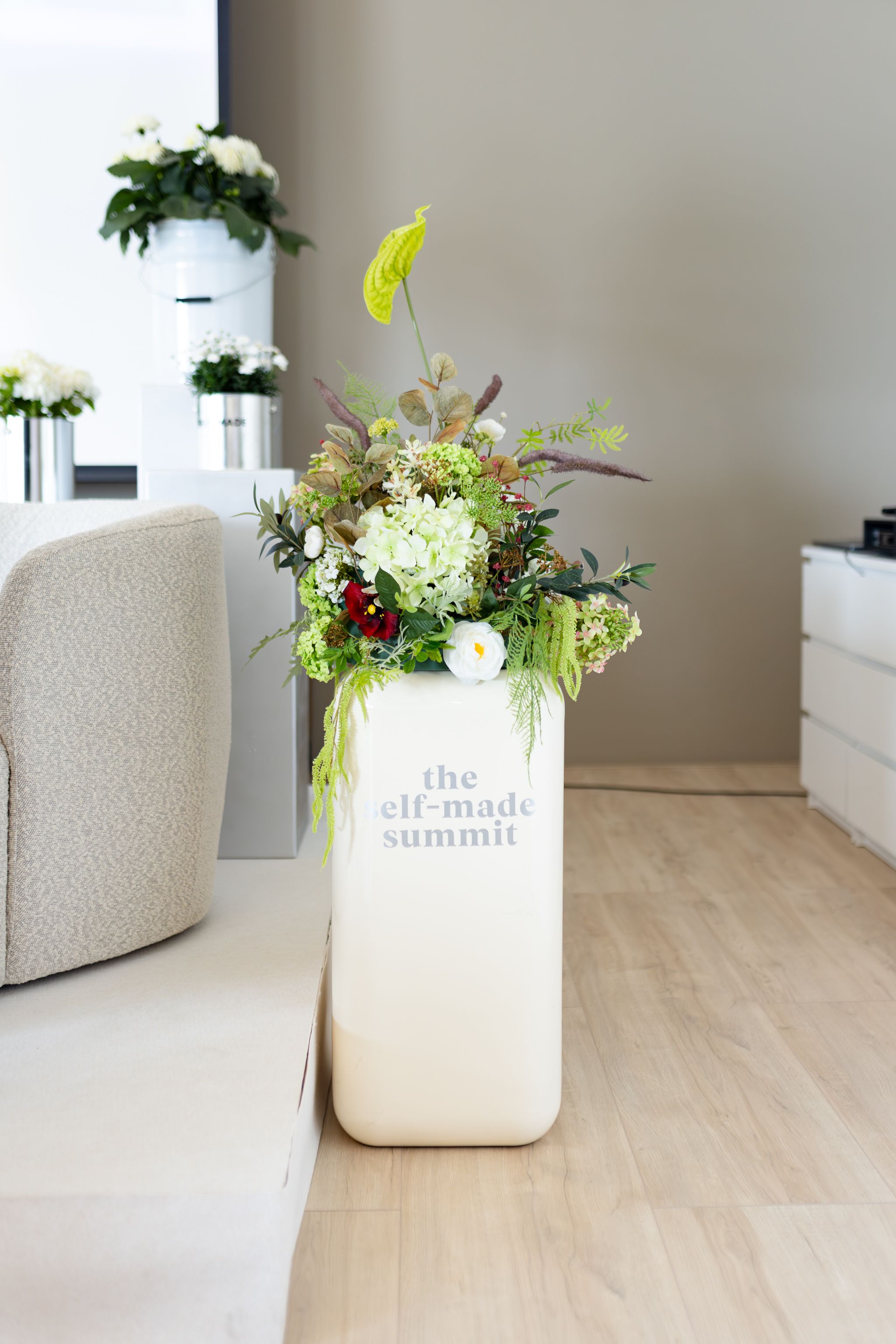 Modern minimalist room interior with white furniture and floral arrangements.