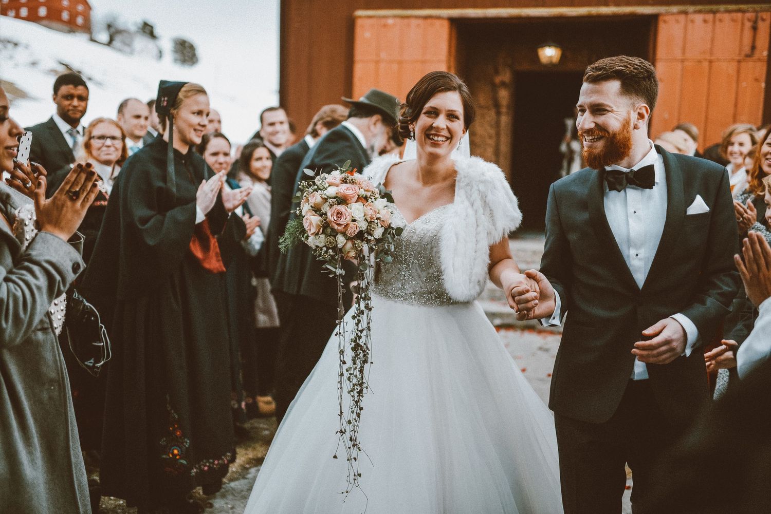 Joyful newlyweds exit their ceremony while guests cheer and celebrate.