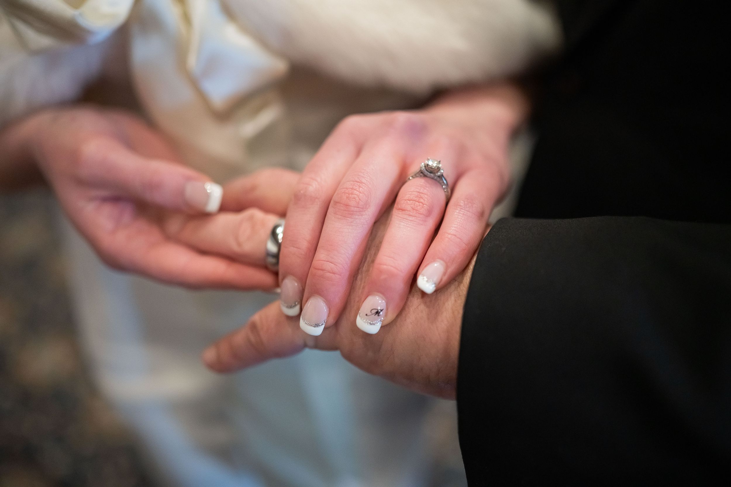 Alyssa's wedding and engagement ring in a tight shot as she places her hand on a church pew