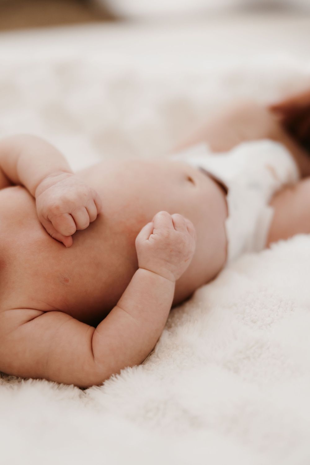 Peaceful sleeping newborn baby lying on soft white blanket.