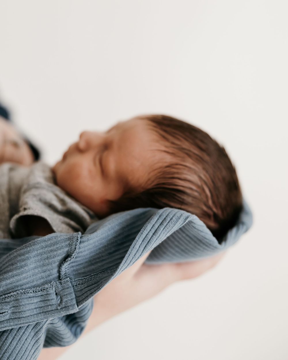 Sleeping baby in gray ribbed clothing captured from above.
