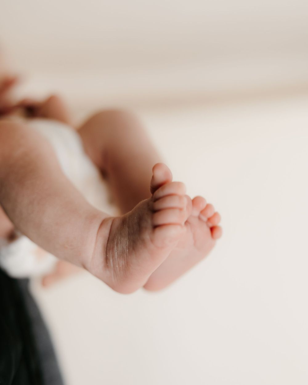 Delicate baby feet captured in soft natural light against white background.
