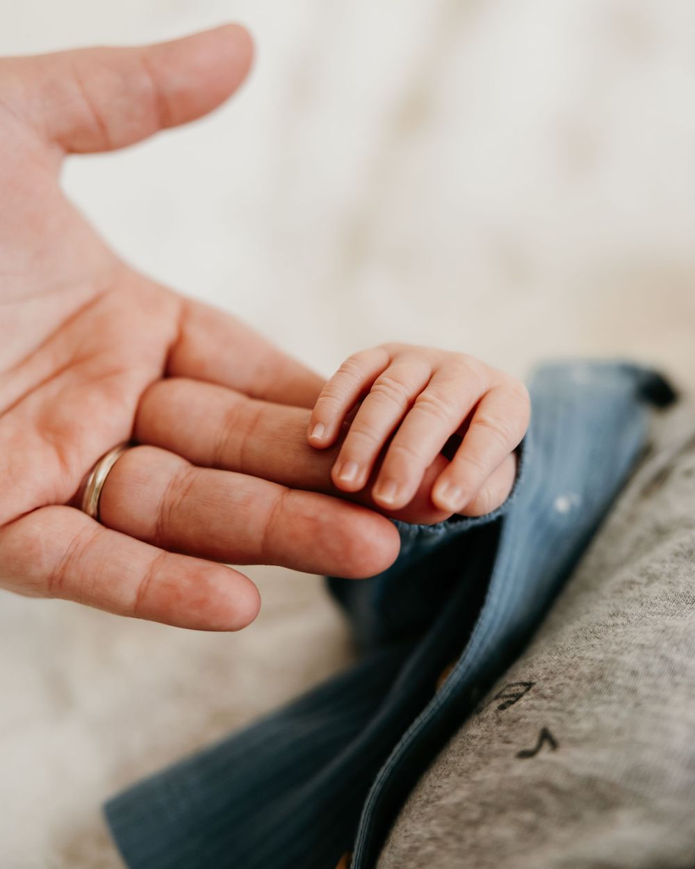 Close-up of tiny baby hand holding adult finger in tender moment.