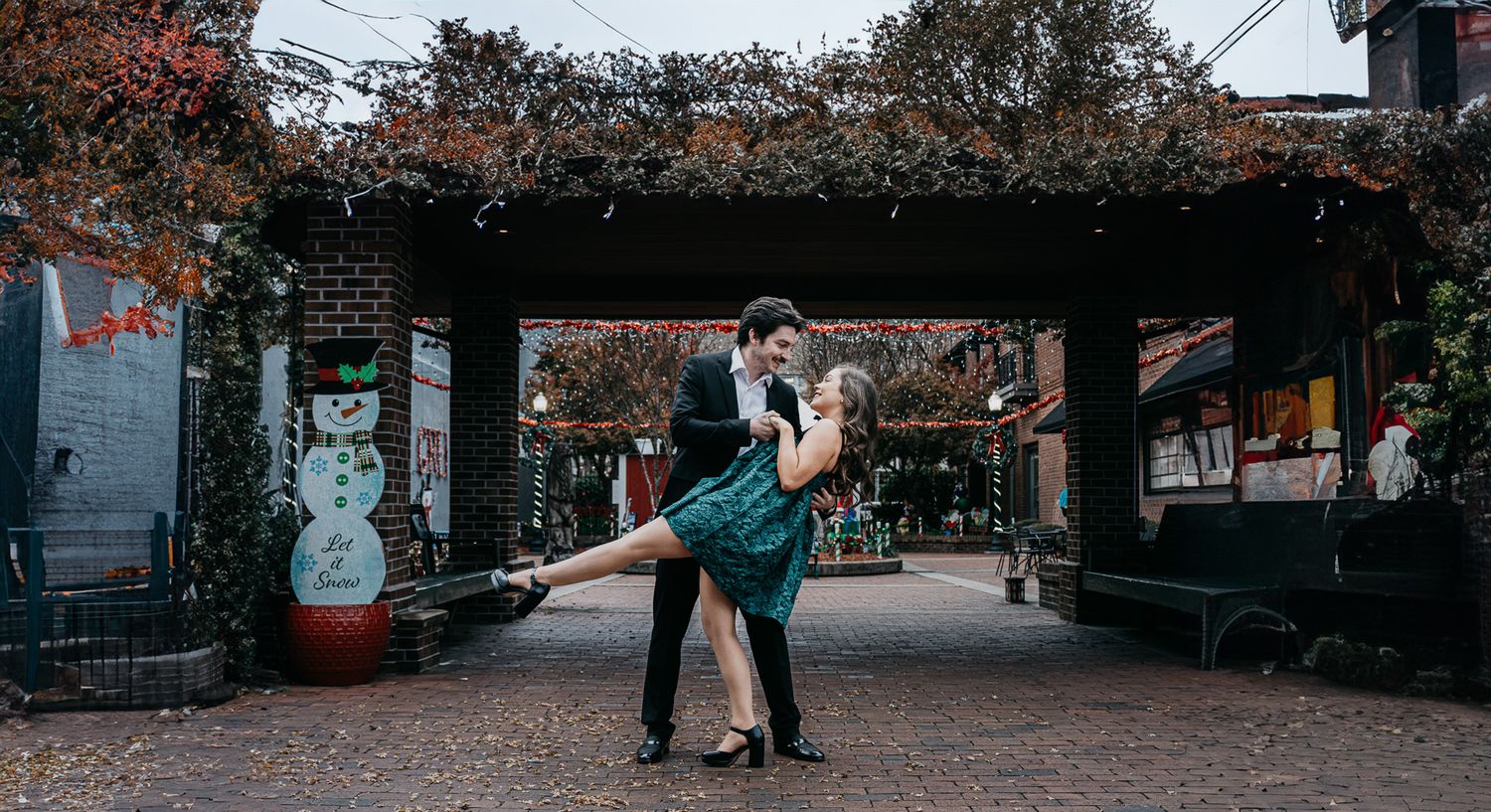 Romantic couple in formal wear dancing under a pergola in an urban setting.