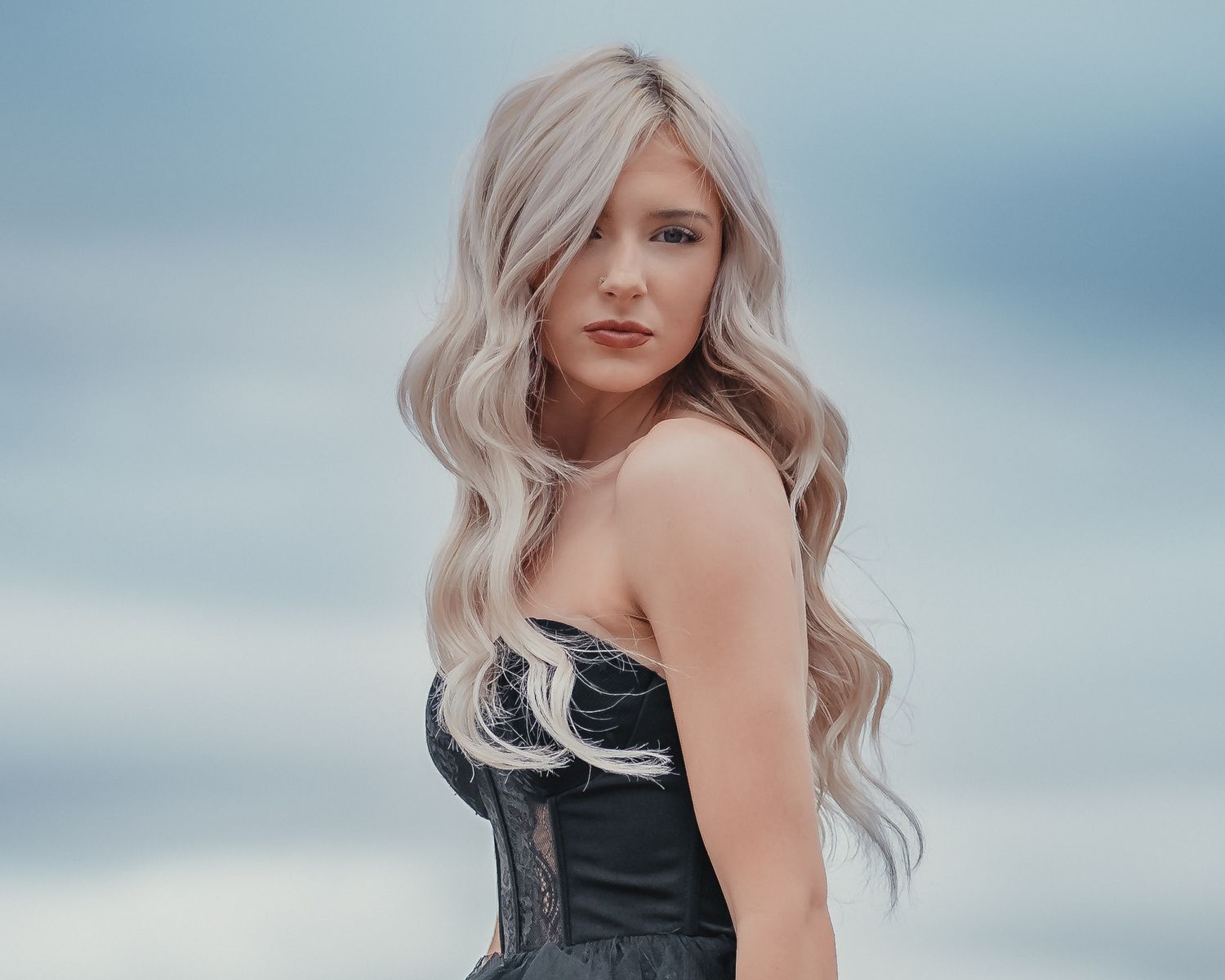 Portrait of a woman with platinum blonde waves against a misty blue backdrop.
