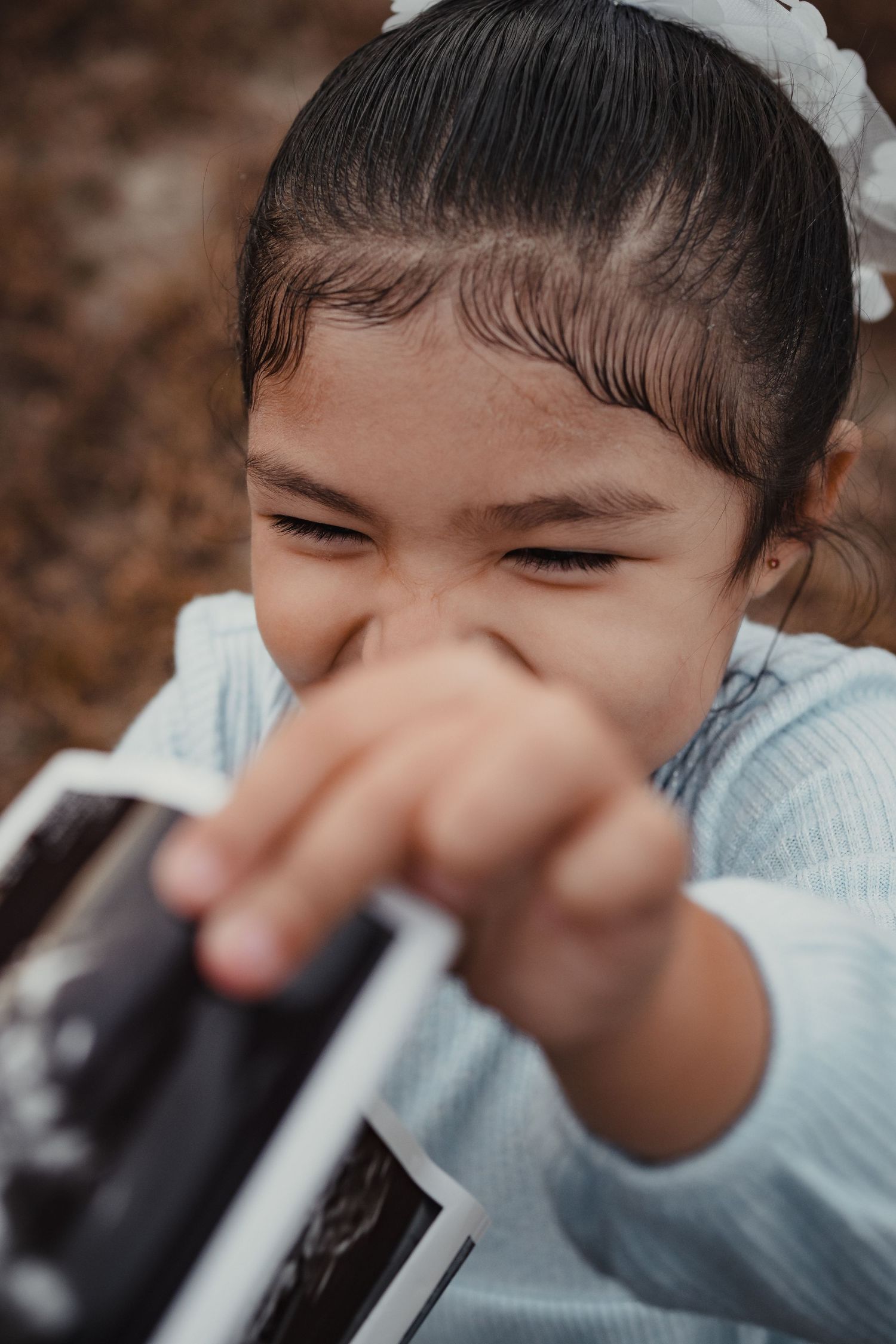 Close up view of a child drinking from a straw against a blurred brown background.