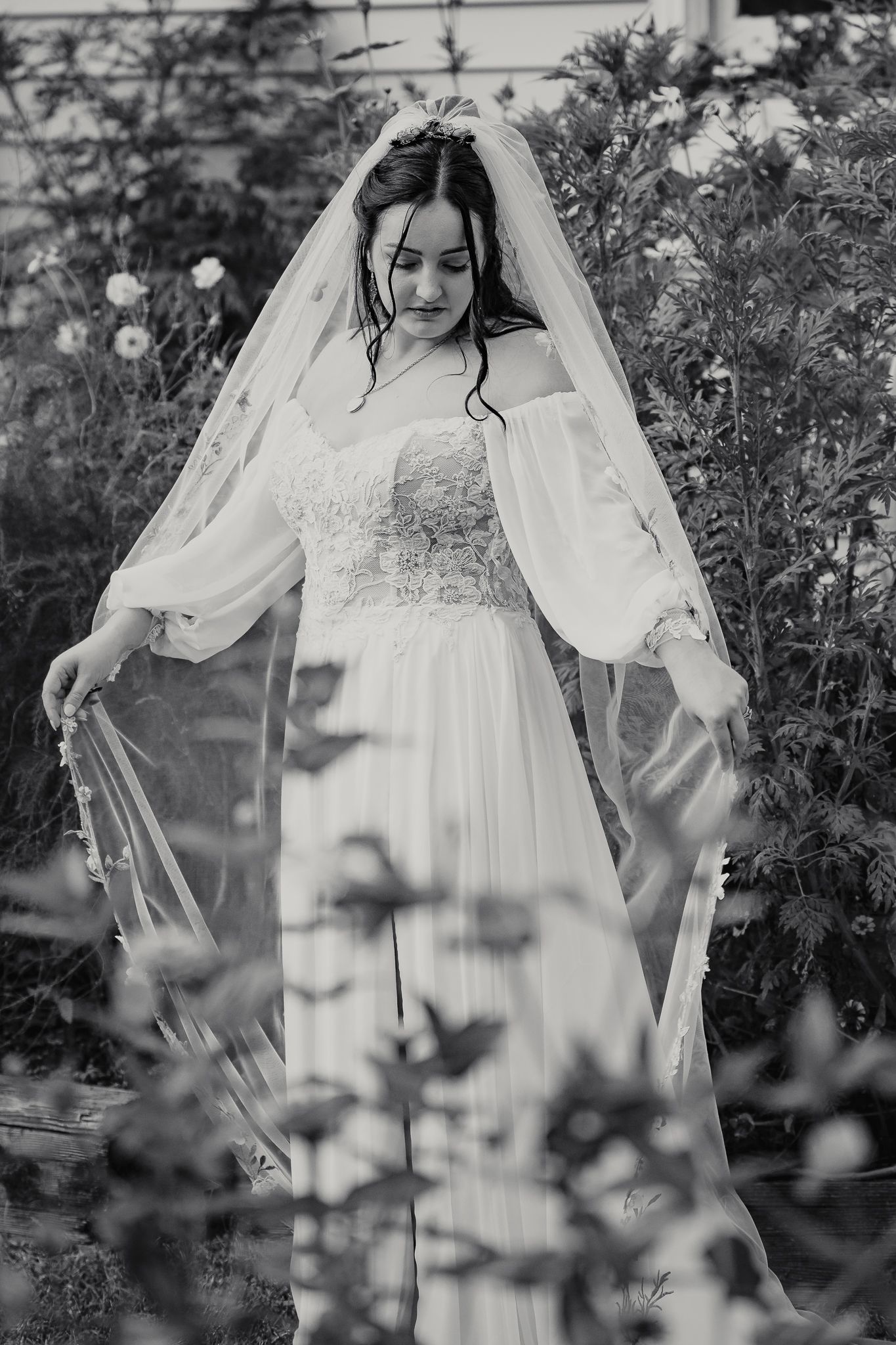 A series of black and white photos showing a figure in a vintage white lace wedding dress and veil among garden foliage.