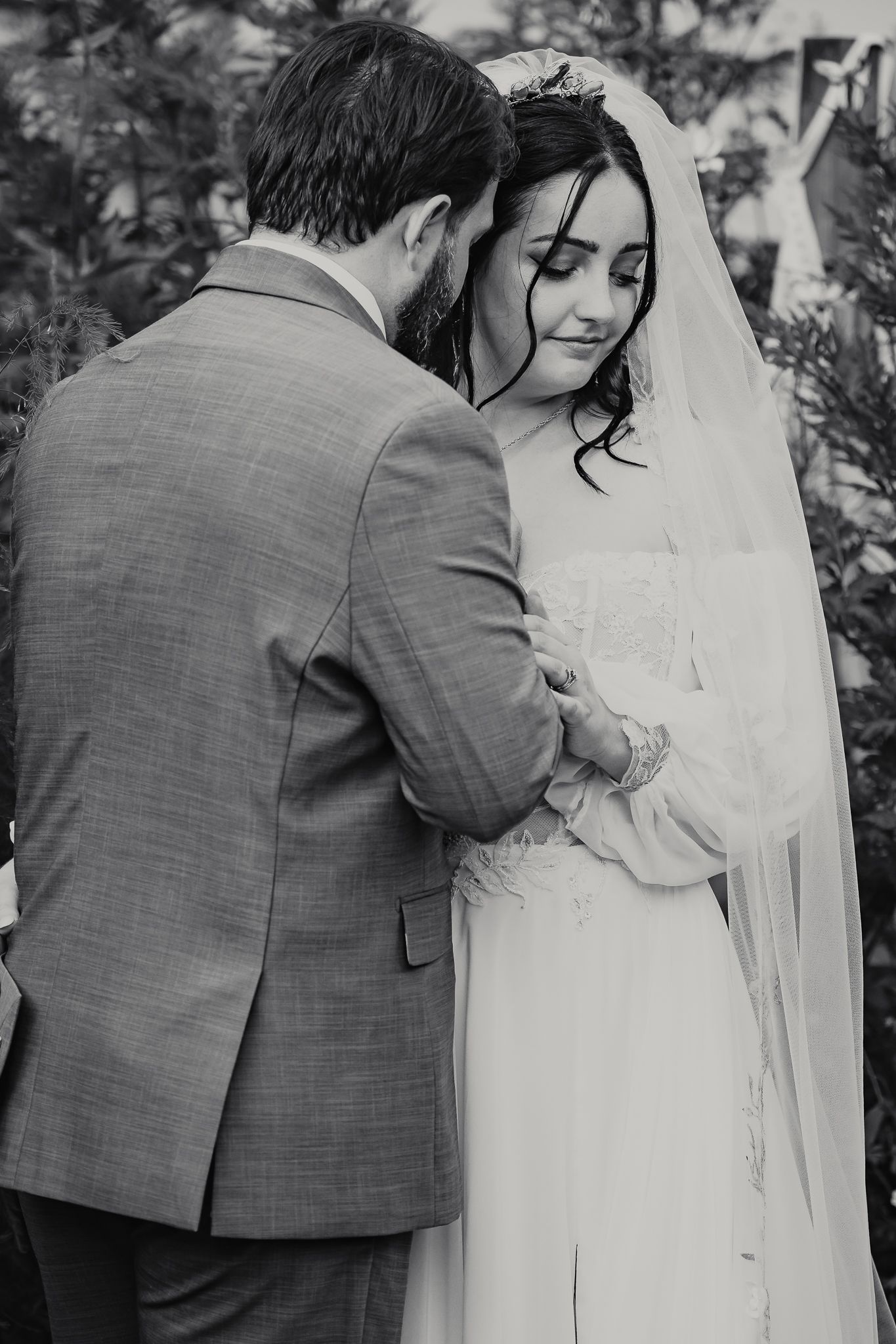 Black and white wedding photo series showing a tender moment between newlyweds in a garden setting.