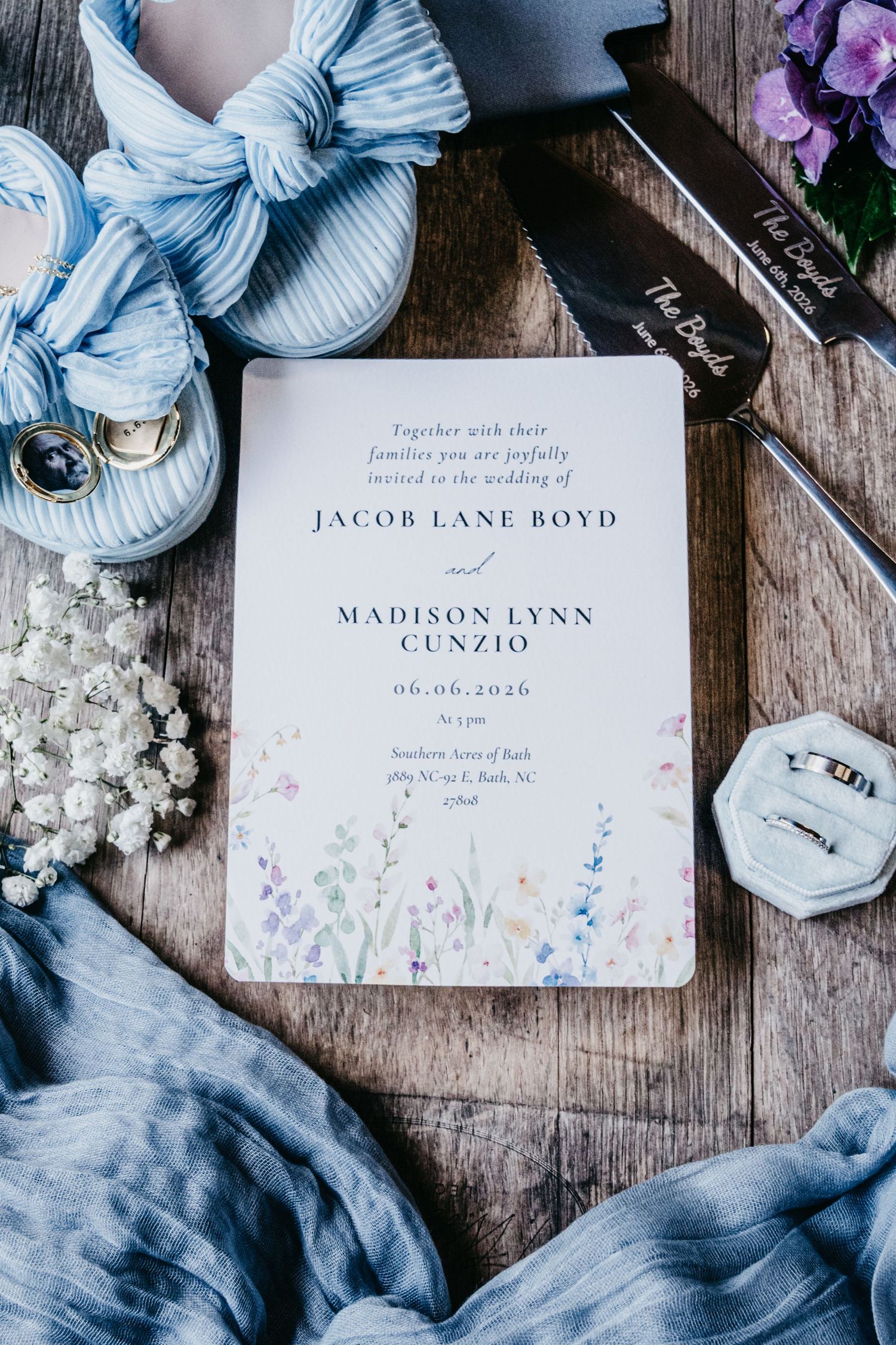 Wedding invitation for Jacob Lane Boyd and Madison Lynn Cunzio on 06.06.2026, surrounded by blue shoes, rings, and wildflowers.