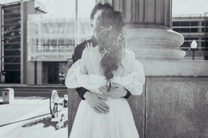 A vintage black and white photo shows a couple embracing on a city street with a dog in the background.